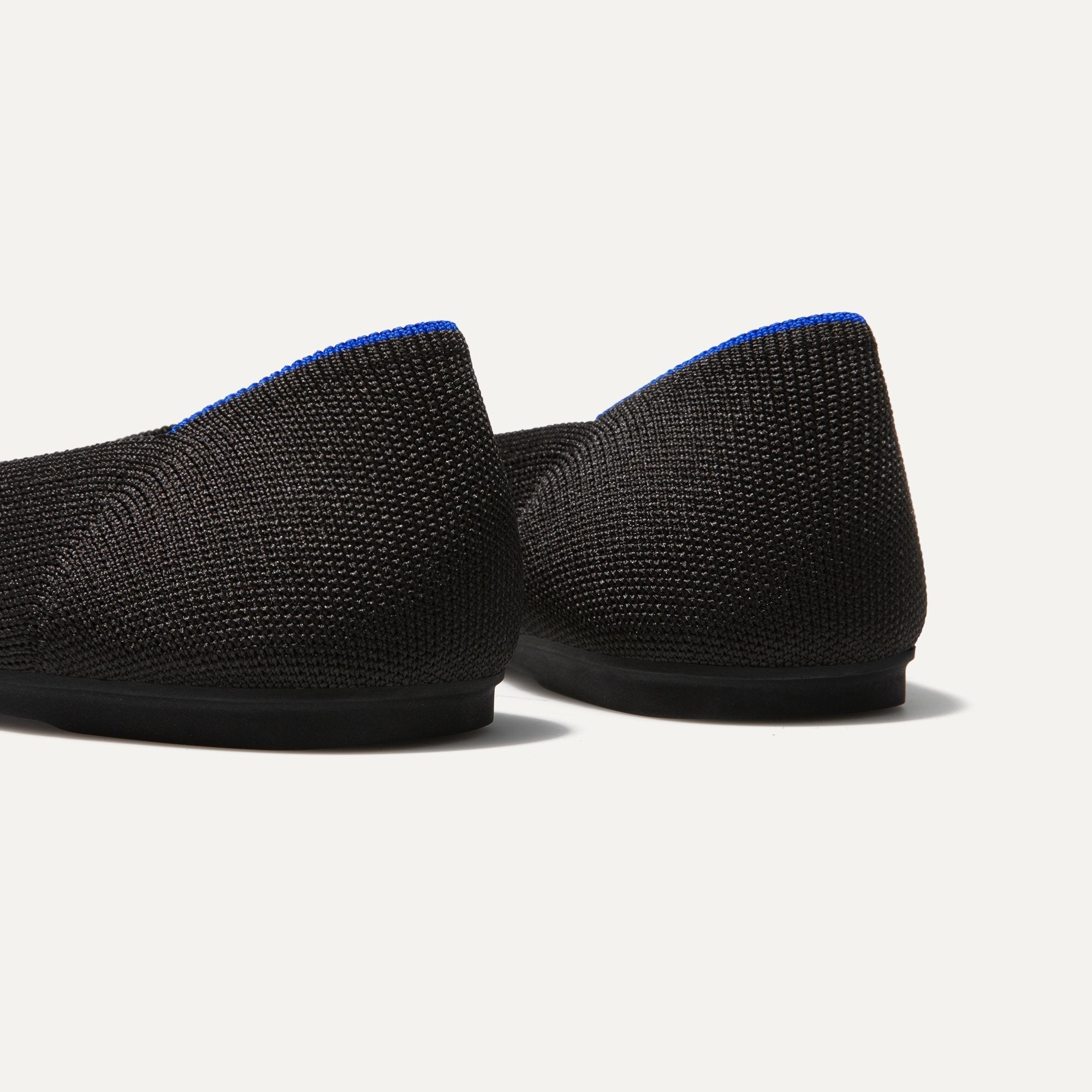 The Flat round toe shoe in Black Solid shown from the back view with the heel detail.