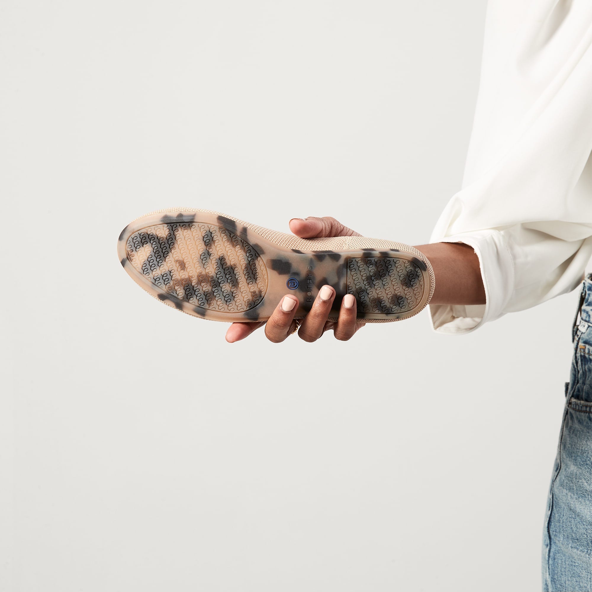 Model holding The Loafer in Ecru and showing the flexible, durable outsoles.