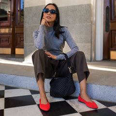 hover | The Daily Crossbody in Black Sand carried by its top handle by a model.