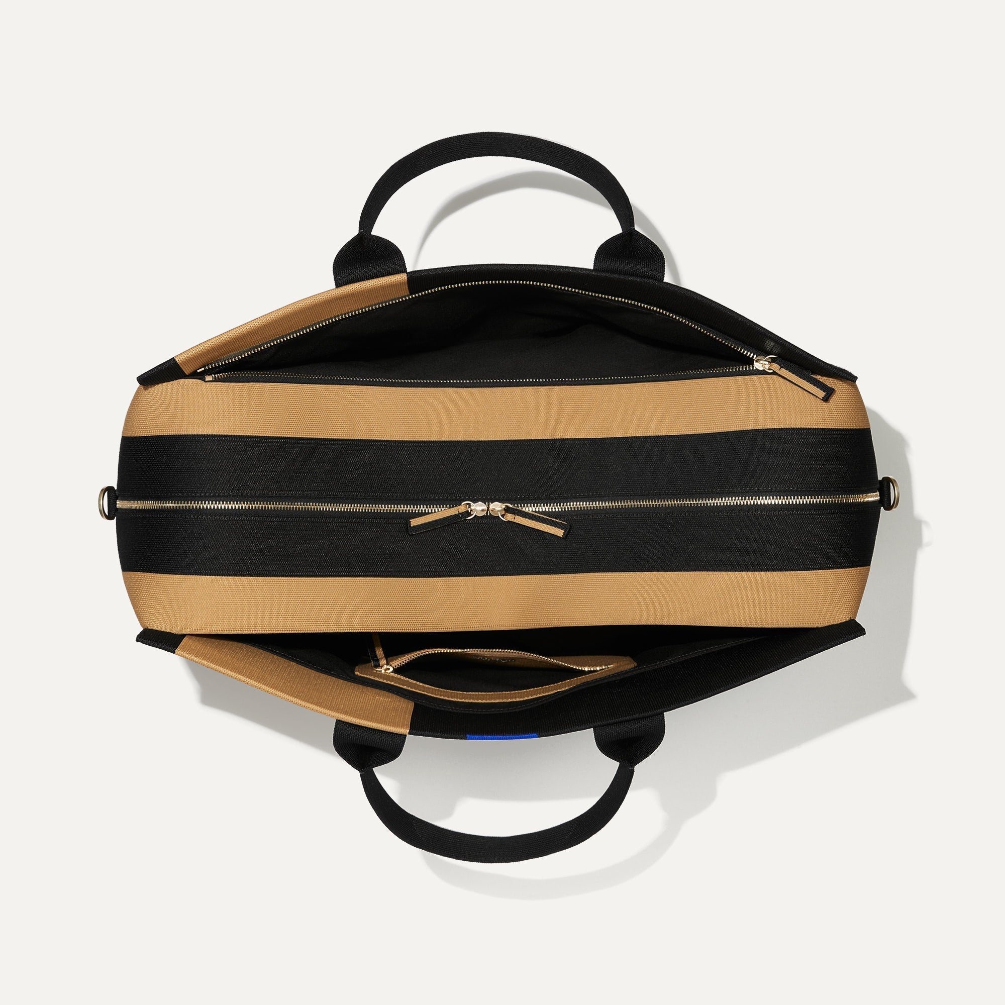 The Weekender in Camel and Black shown from the top with zipper side compartment and magnetic side compartment open.