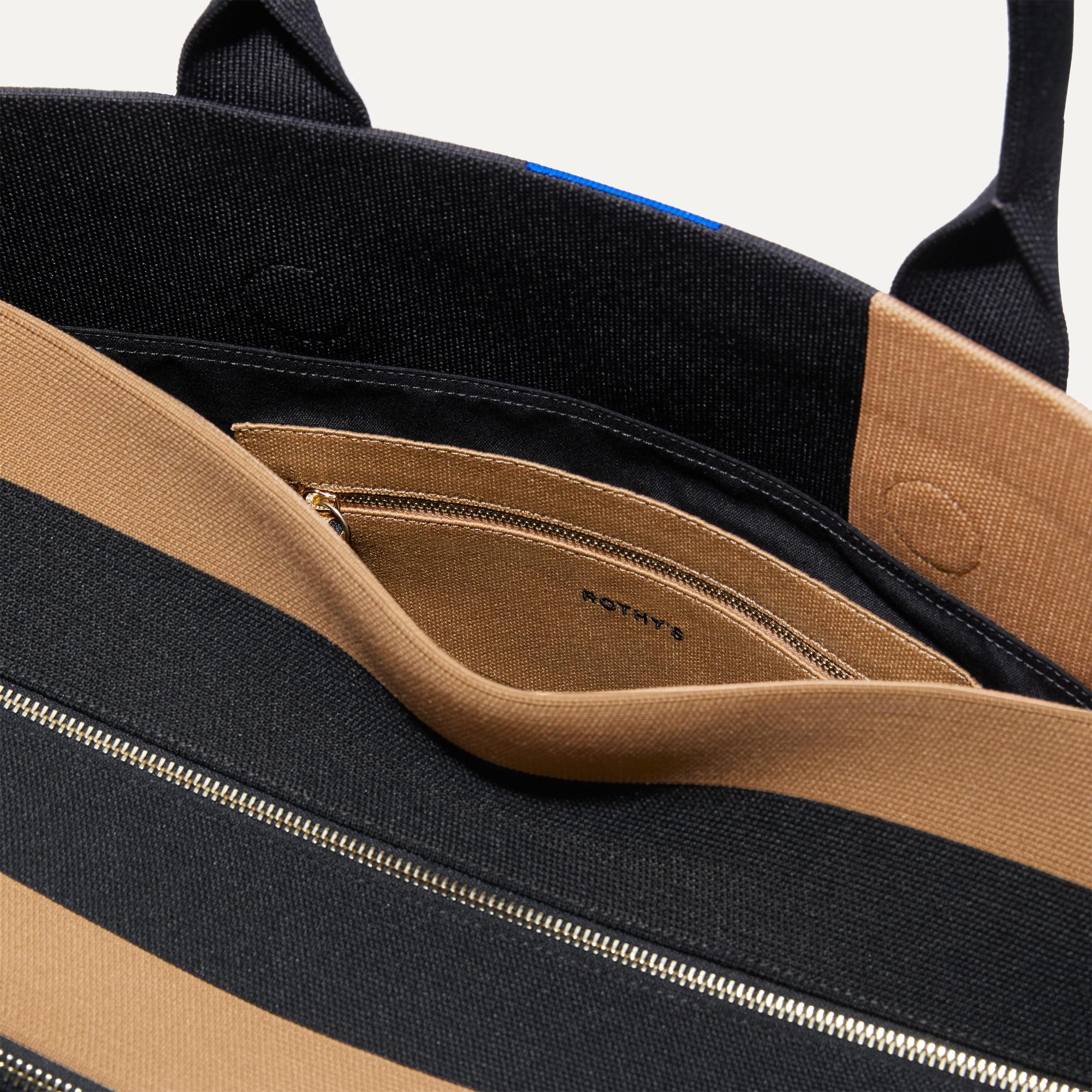 The Weekender in Camel and Black shown with a close up view of the interior zipper pocket in the magnetic side compartment.
