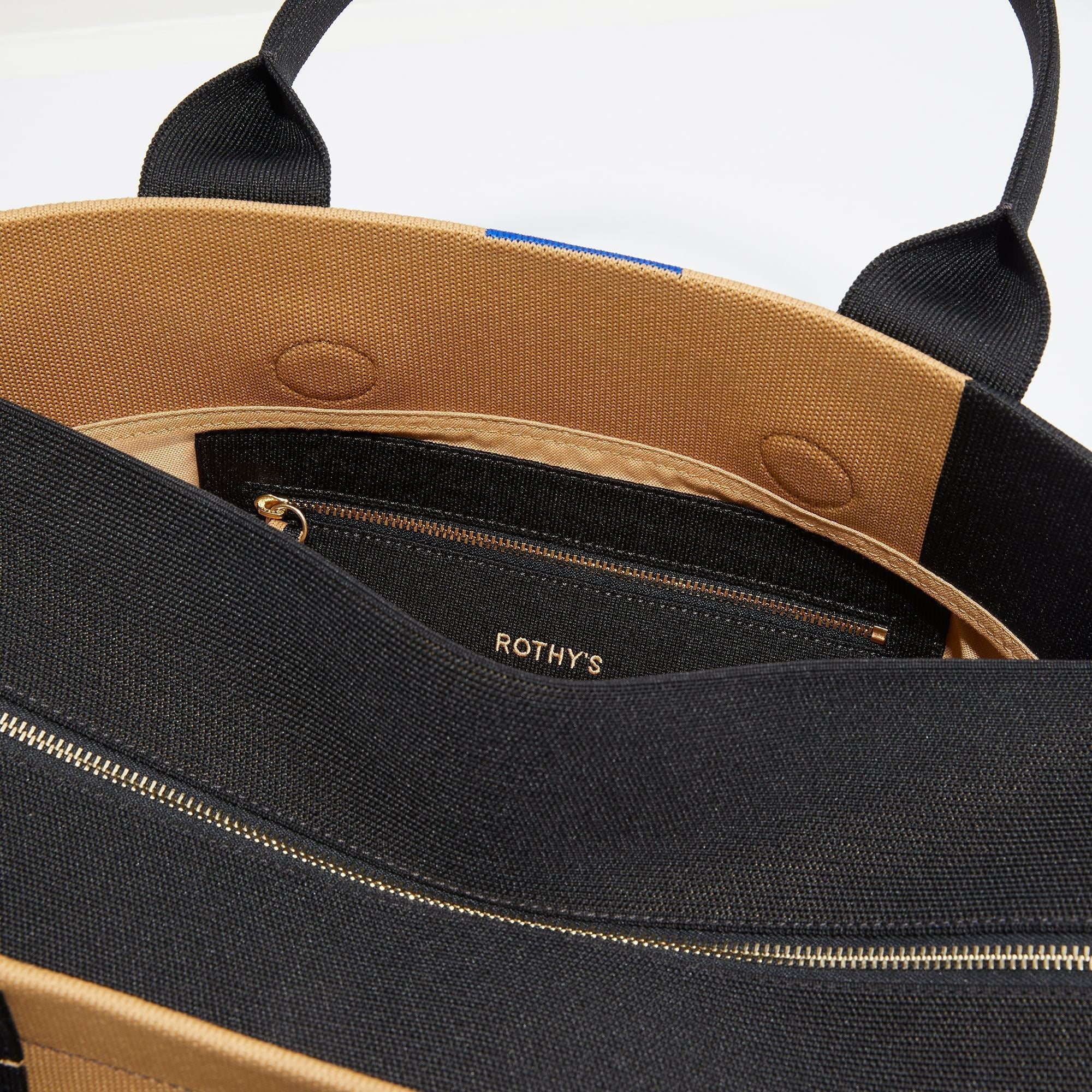 The Overnighter in Camel and Black shown with a close up view of the interior zipper pocket in the magnetic side compartment.