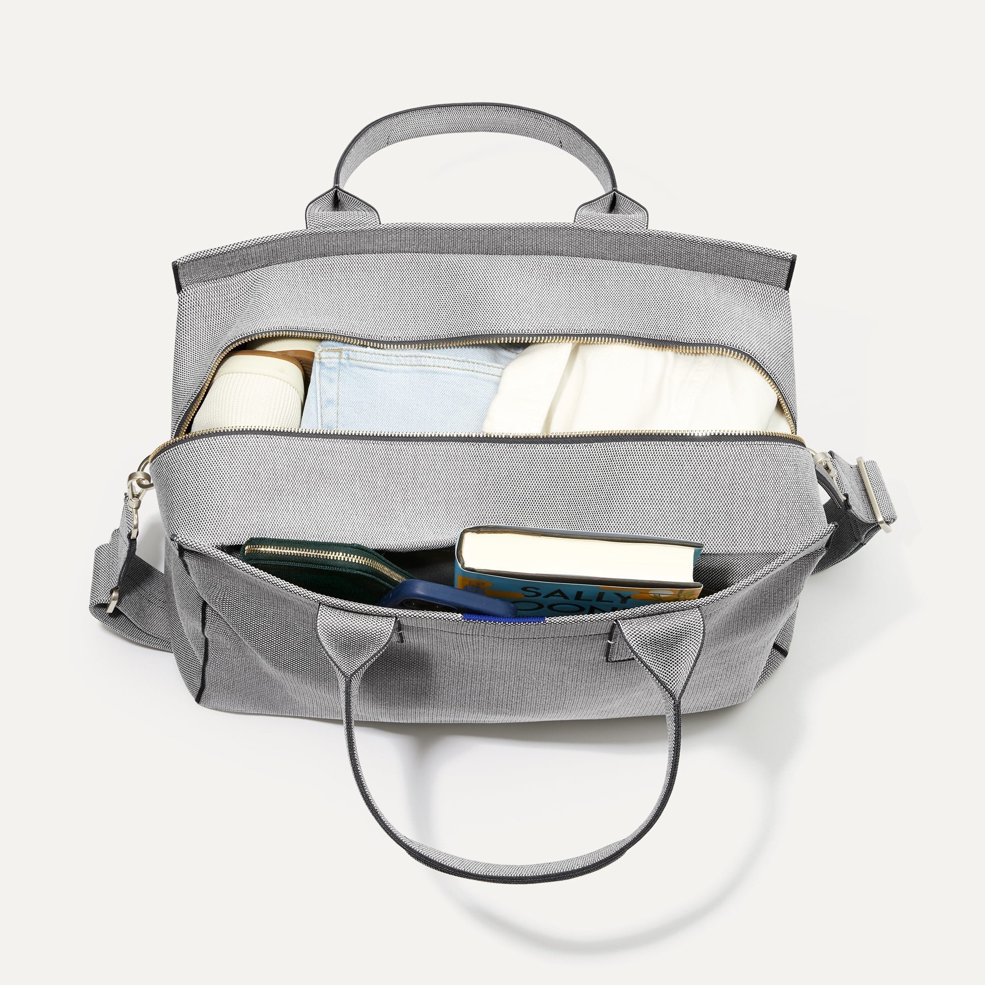 hover | The Overnighter in Stone Grey shown with two compartments packed with clothes, shoes, books, a wallet and a phone.