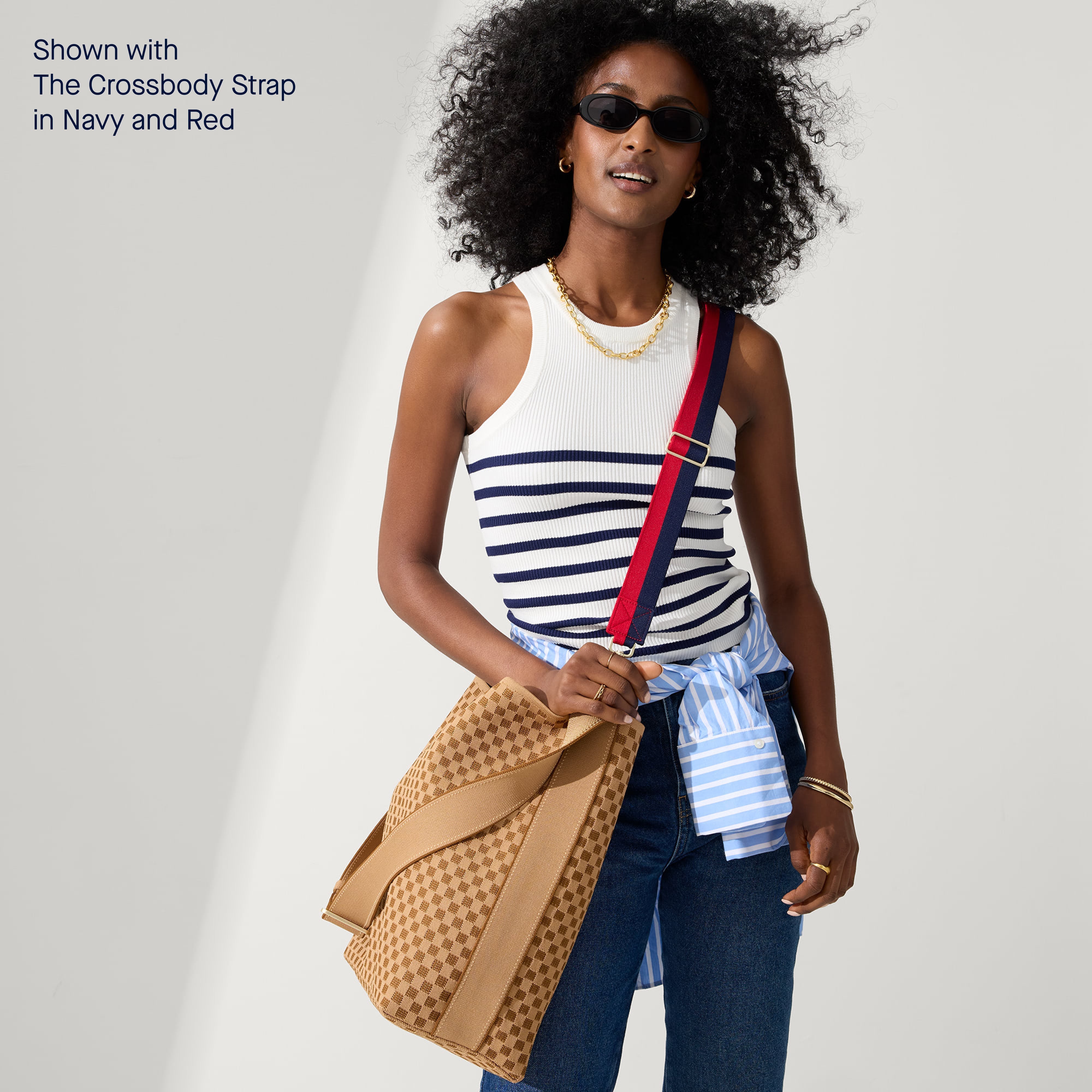 The Bucket Bag in Hazelnut shown with The Crossbody Strap in Navy and Red, worn by a model.