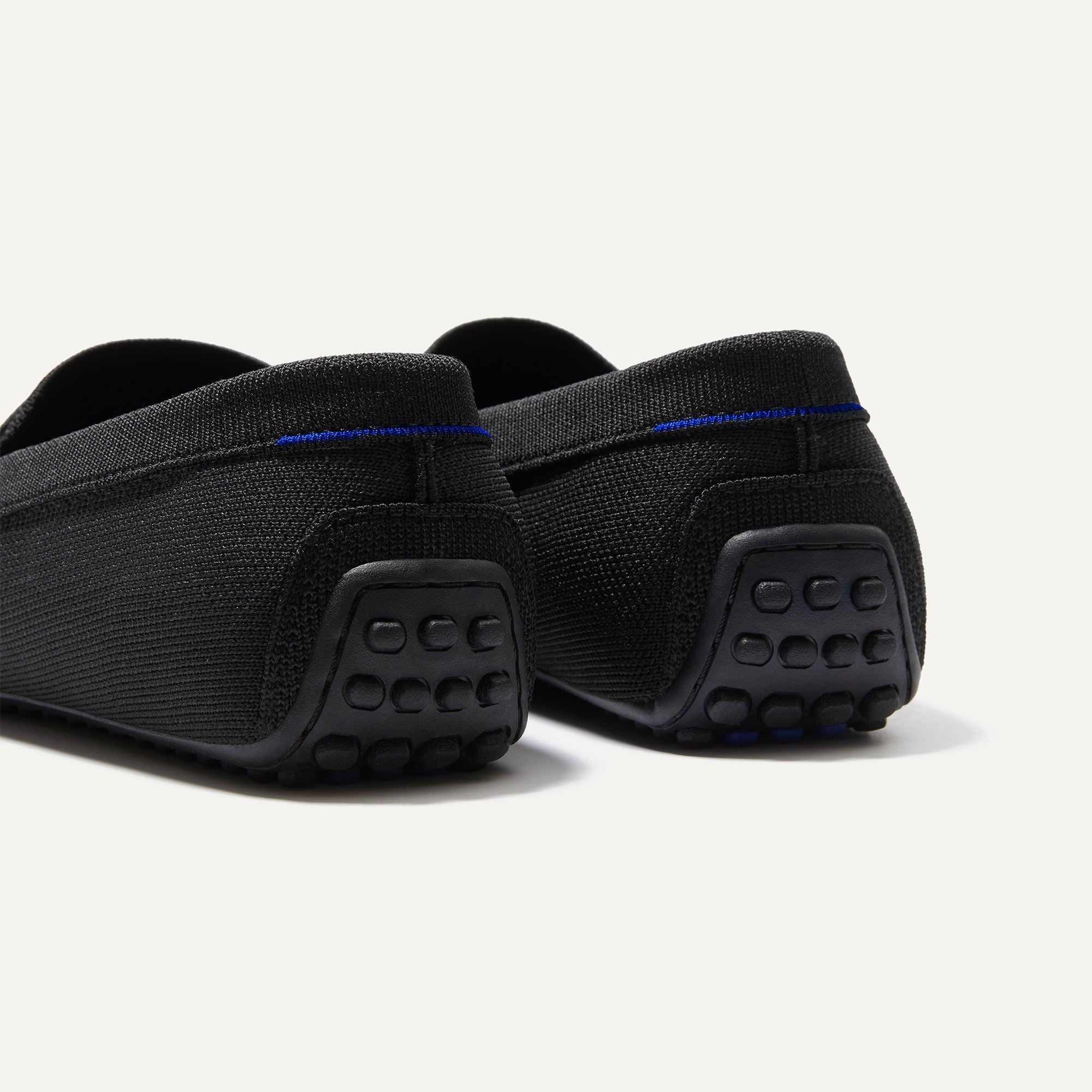 Close up of the heel of The Driving Loafer in Black, with raised nub outsoles and Rothy's signature blue halo. 