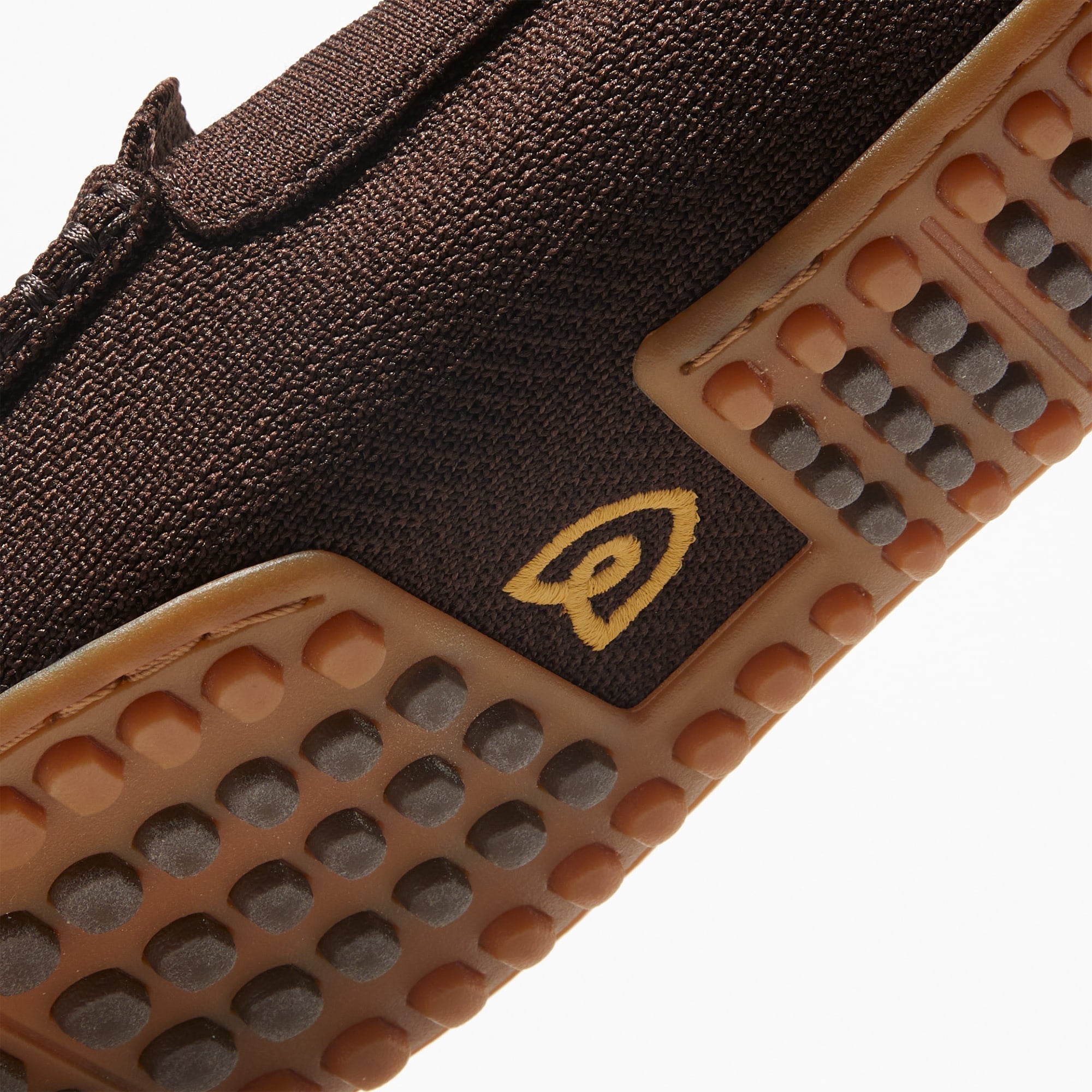 Close up of the outsoles of The Driving Loafer in Brown Herringbone, with raised nub details and the Rothy's signet on the base of the shoe. 