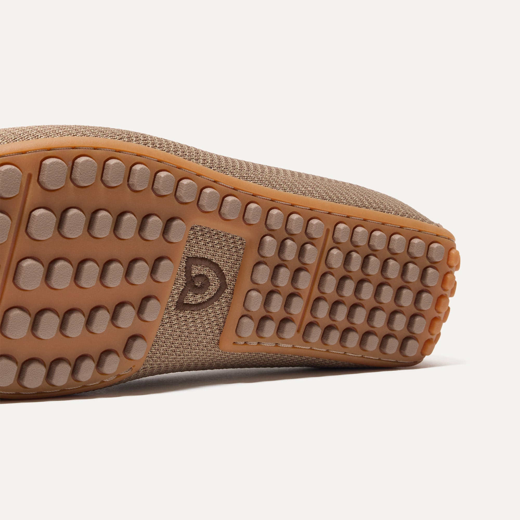 Close up of the outsoles of The Driving Loafer in Portobello Herringbone, with raised nub details and the Rothy's signet on the base of the shoe. 