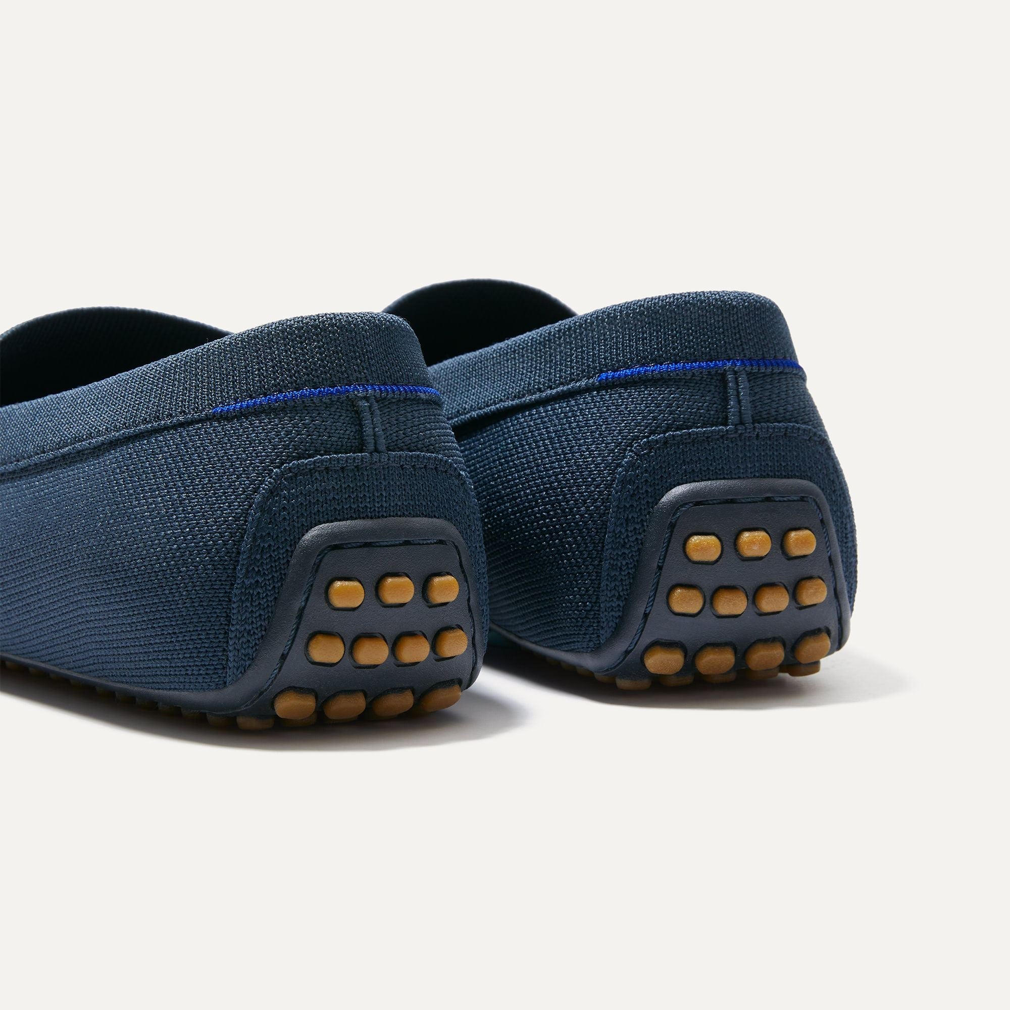Close up of the heel of The Driving Loafer in Navy, with raised nub outsoles and Rothy's signature blue halo. 