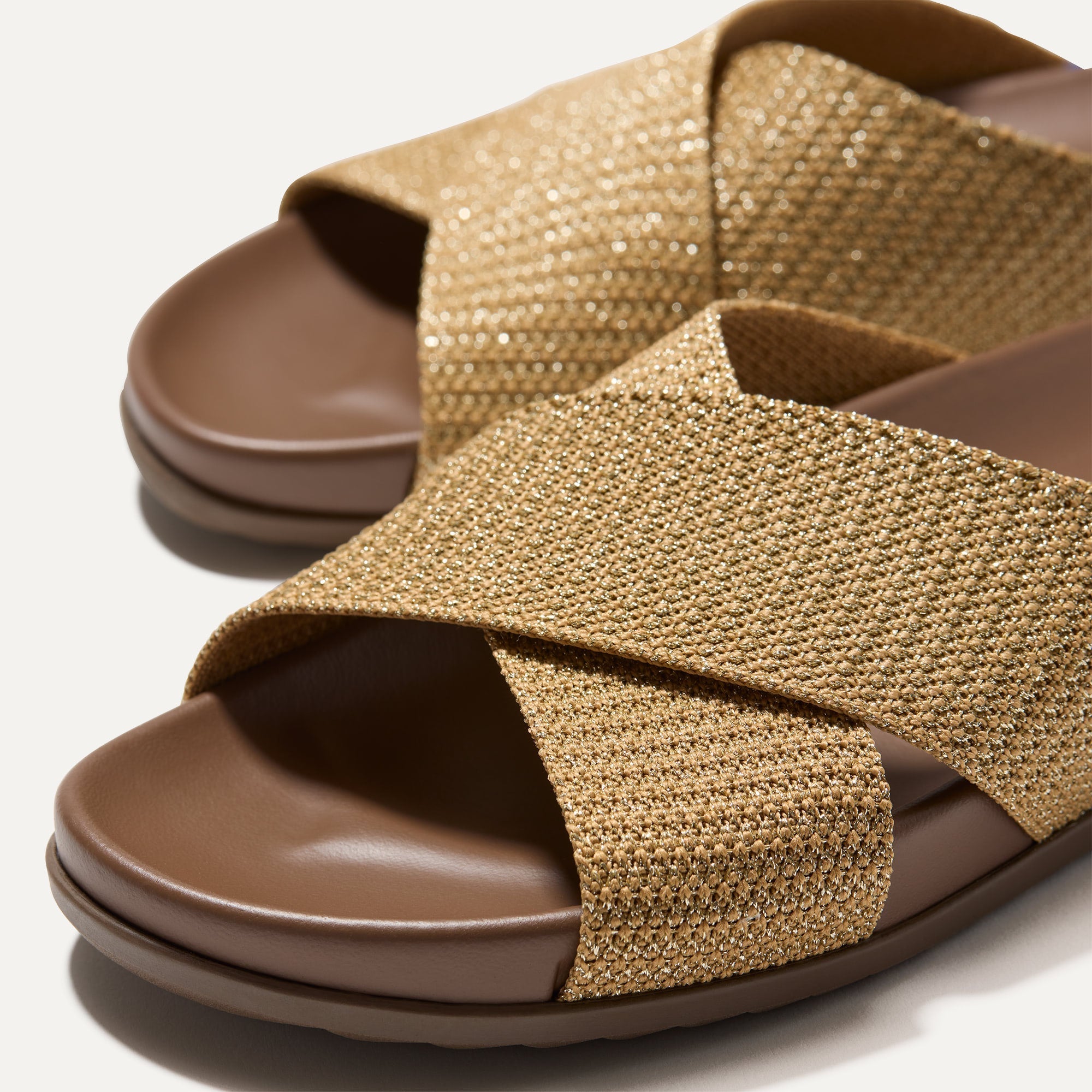 Close up of the crossing knit straps and toe of The Weekend Slide in Golden Sun, shown in diagonal view. 