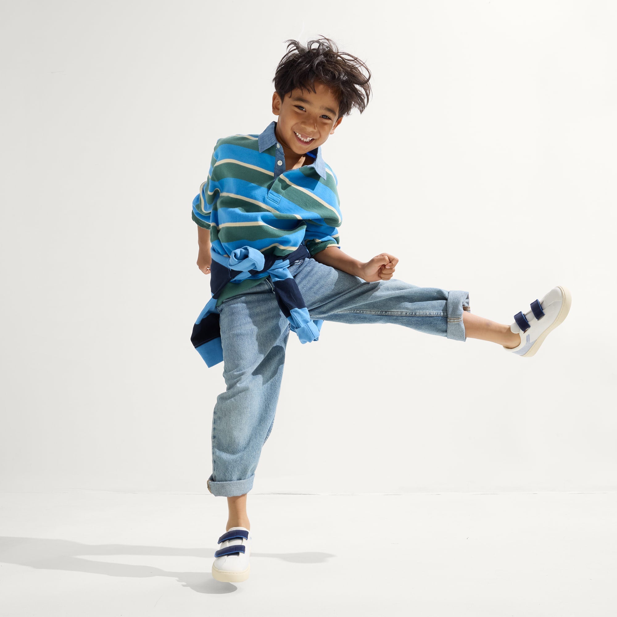 A child modeling The Kids Strap Sneaker in Blue Raspberry.