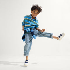 A child modeling The Kids Strap Sneaker in Blue Raspberry.