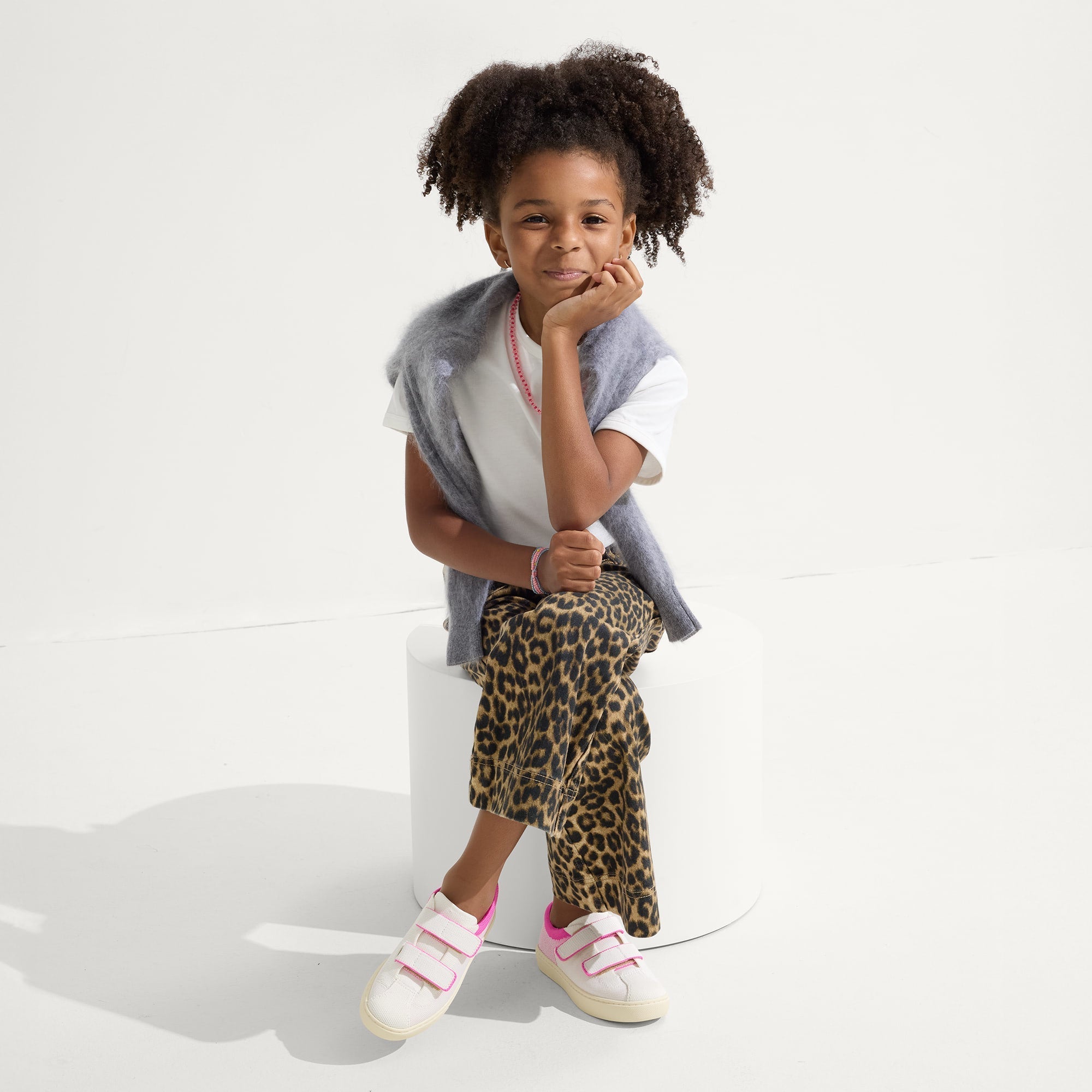 A child modeling The Kids Strap Sneaker in Pink Taffy.