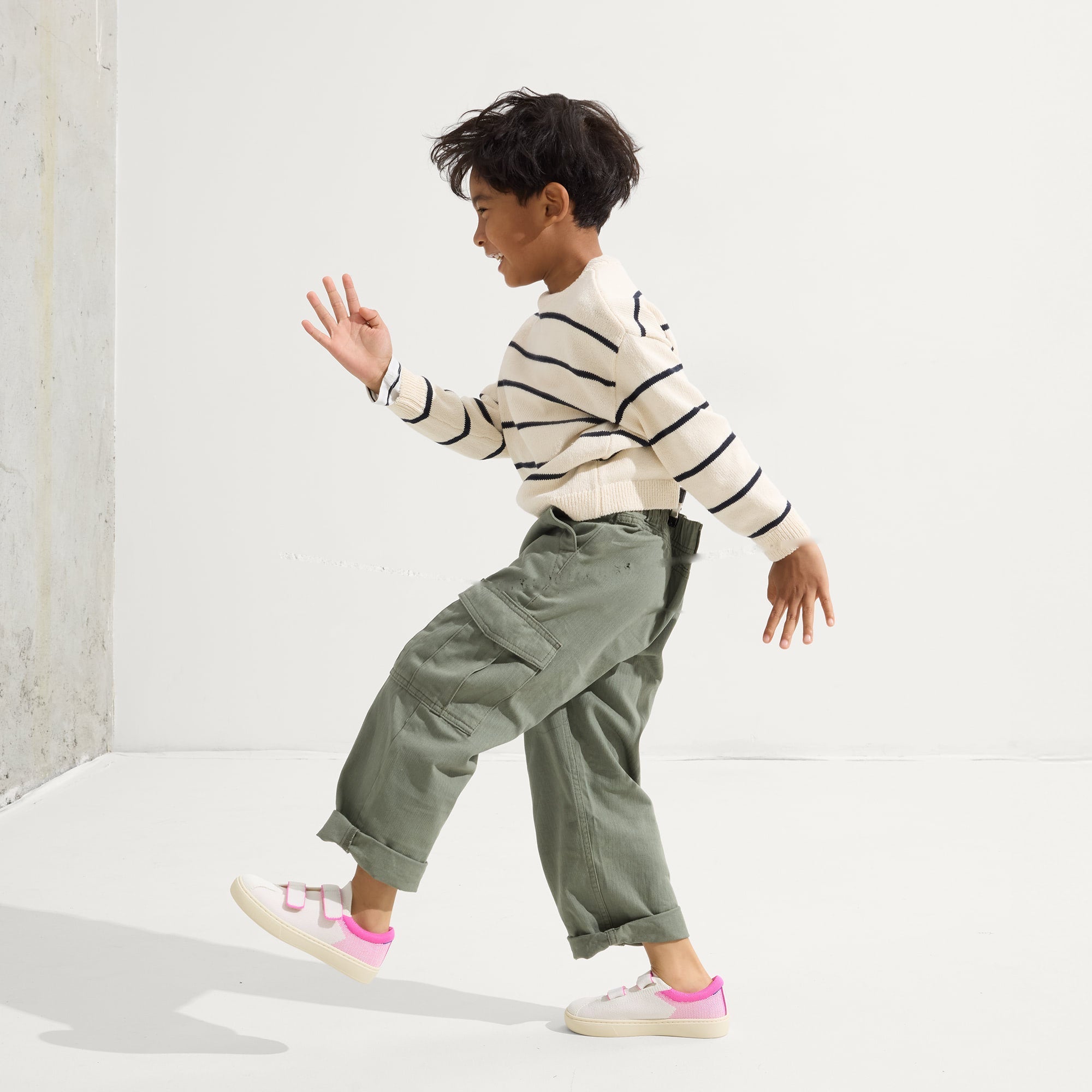 A child modeling The Kids Strap Sneaker in Pink Taffy.