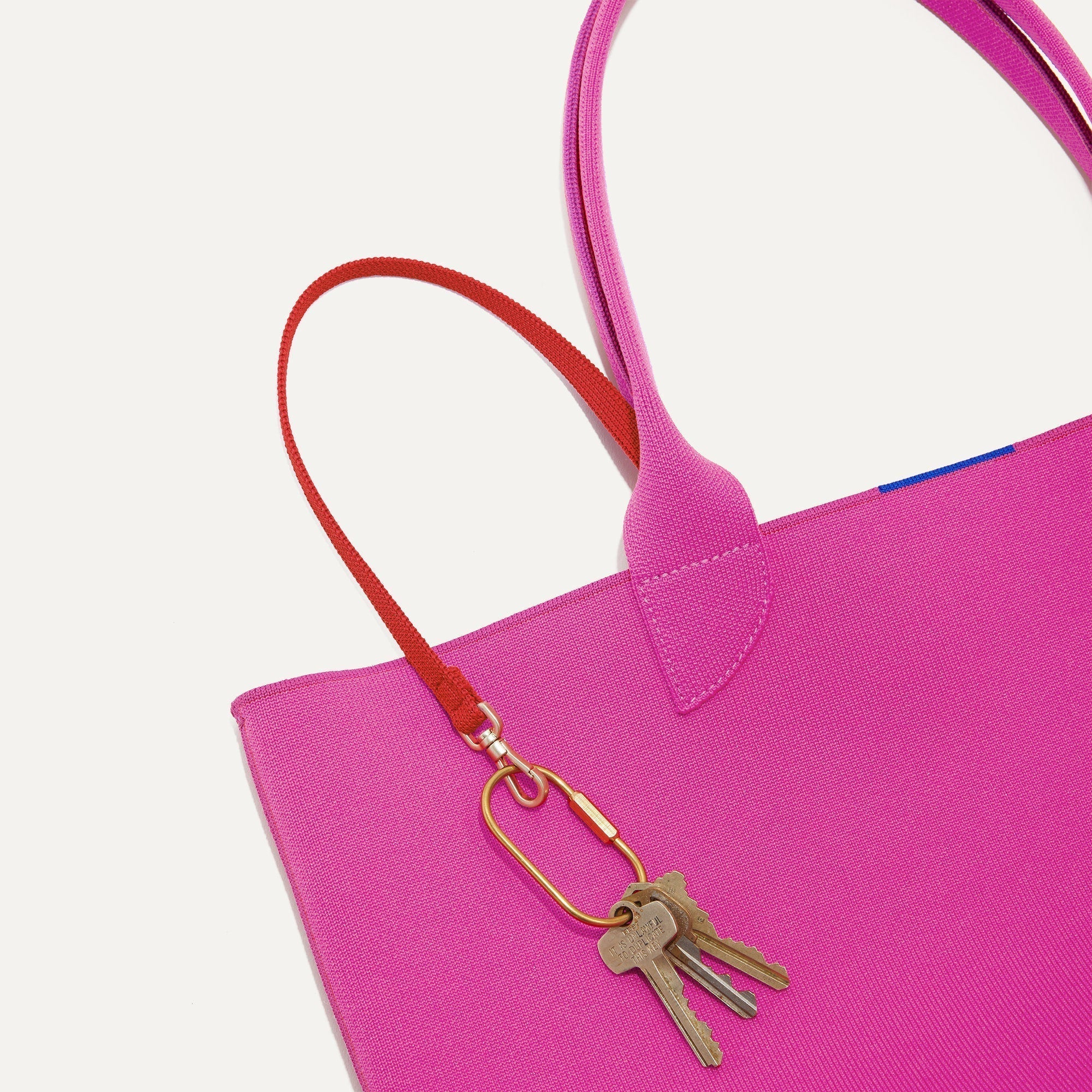 Close up of the handles and key leash detail of The Lightweight Tote in Dragon Fruit.