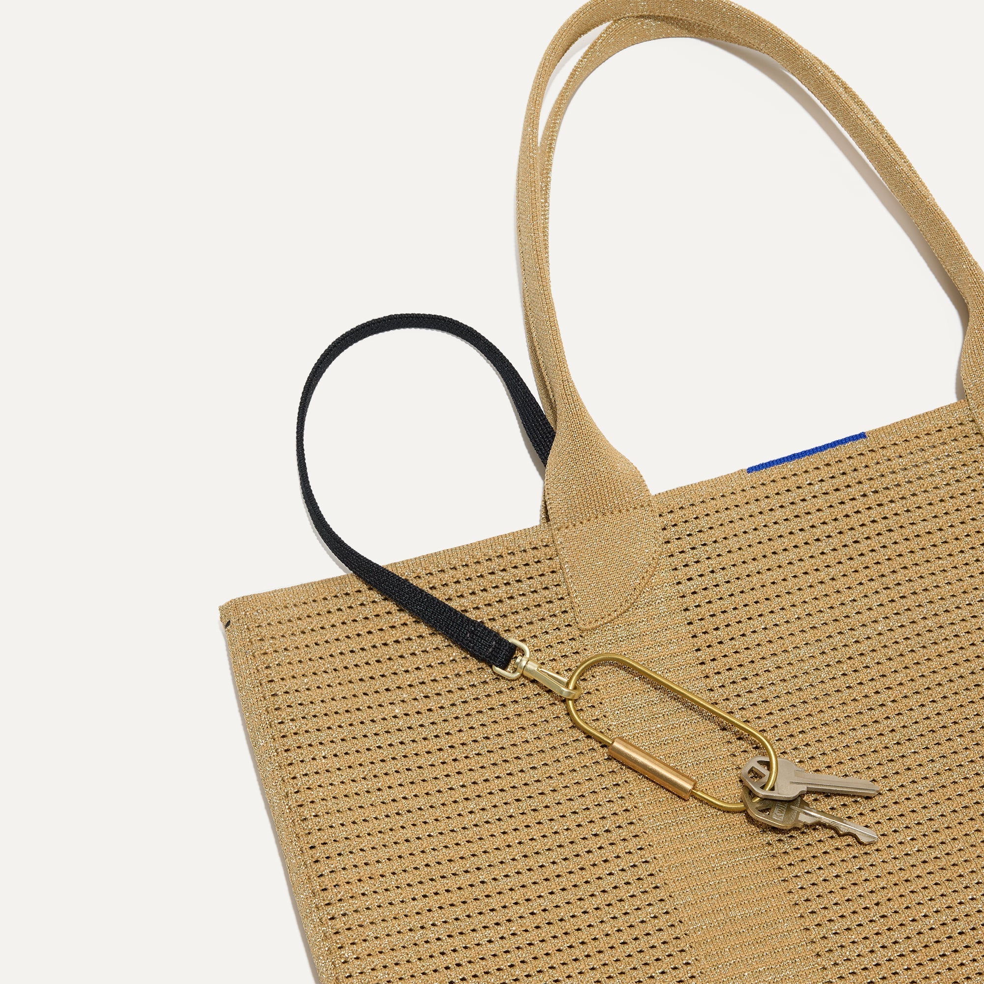 Close up of the handles and key leash detail of The Lightweight Tote in Golden Perf.