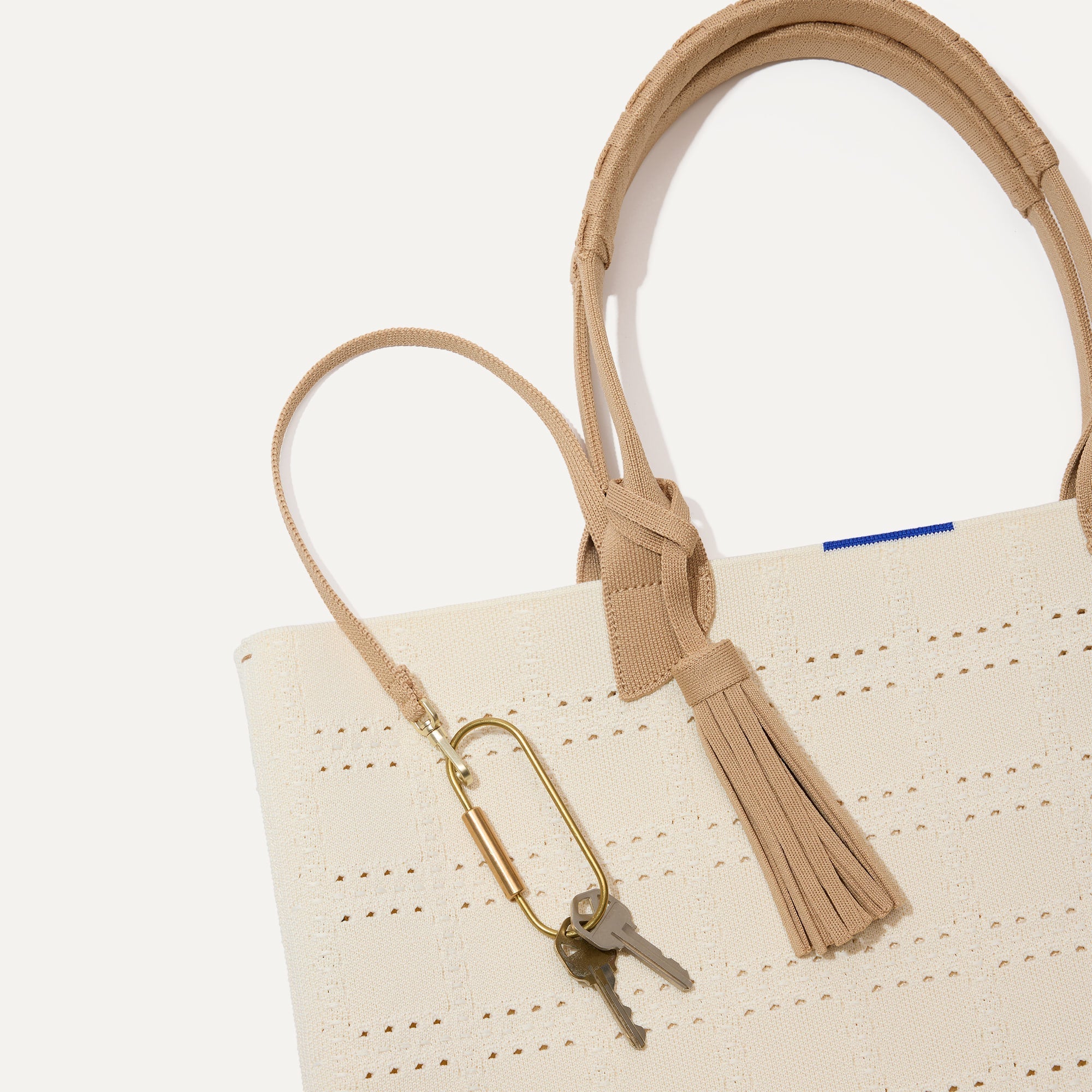 Close up of the handles and key leash detail of The Lightweight Tote in  Ivory Perf.