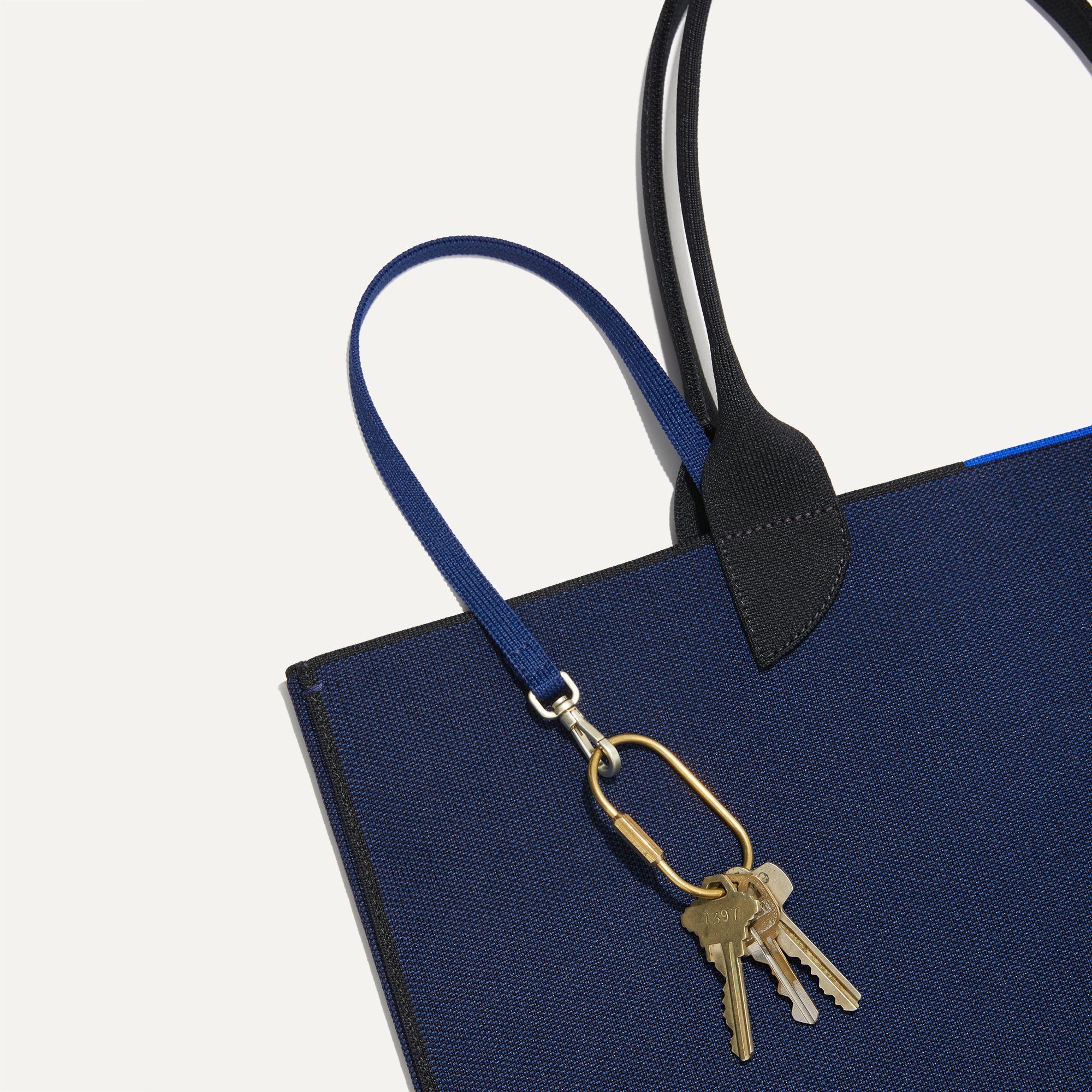 Close up of the handles and key leash detail of The Lightweight Tote in Sapphire and Onyx.
