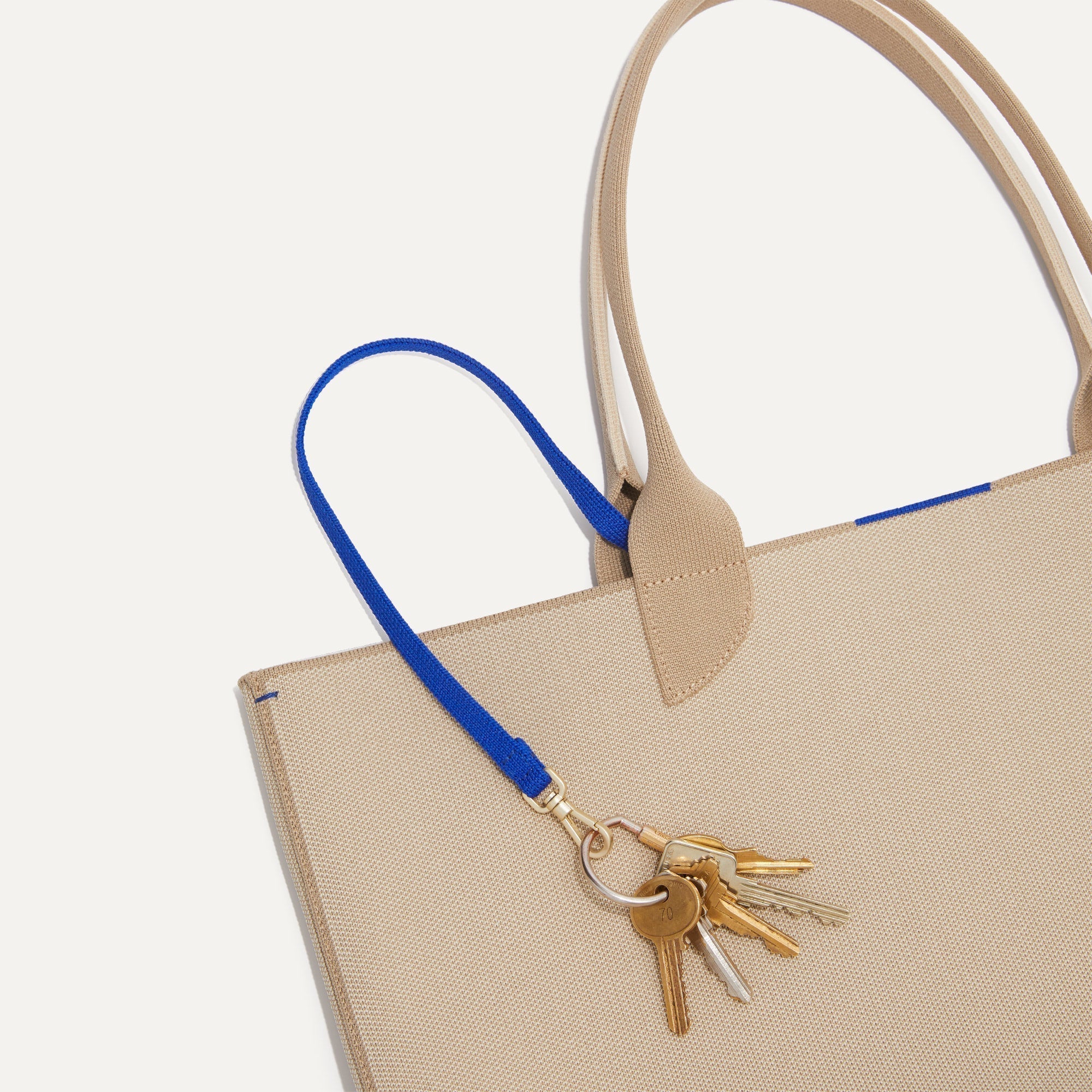 Close up of the handles and key leash detail of The Lightweight Tote in Soft Sesame.