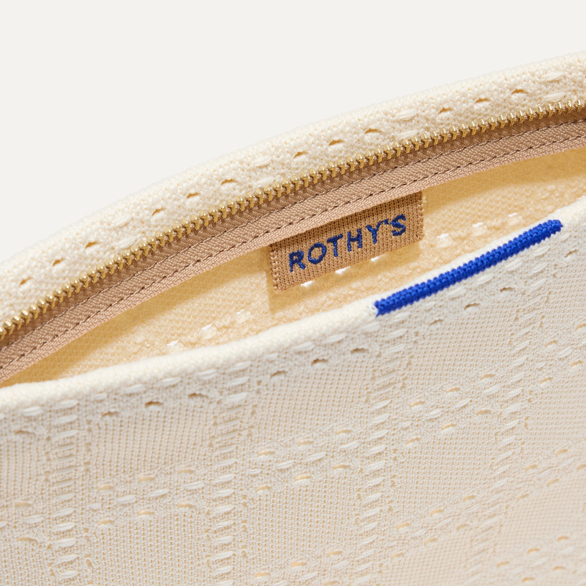 A closeup of The Wristlet in Ivory Perf, focusing on the inner card slip.