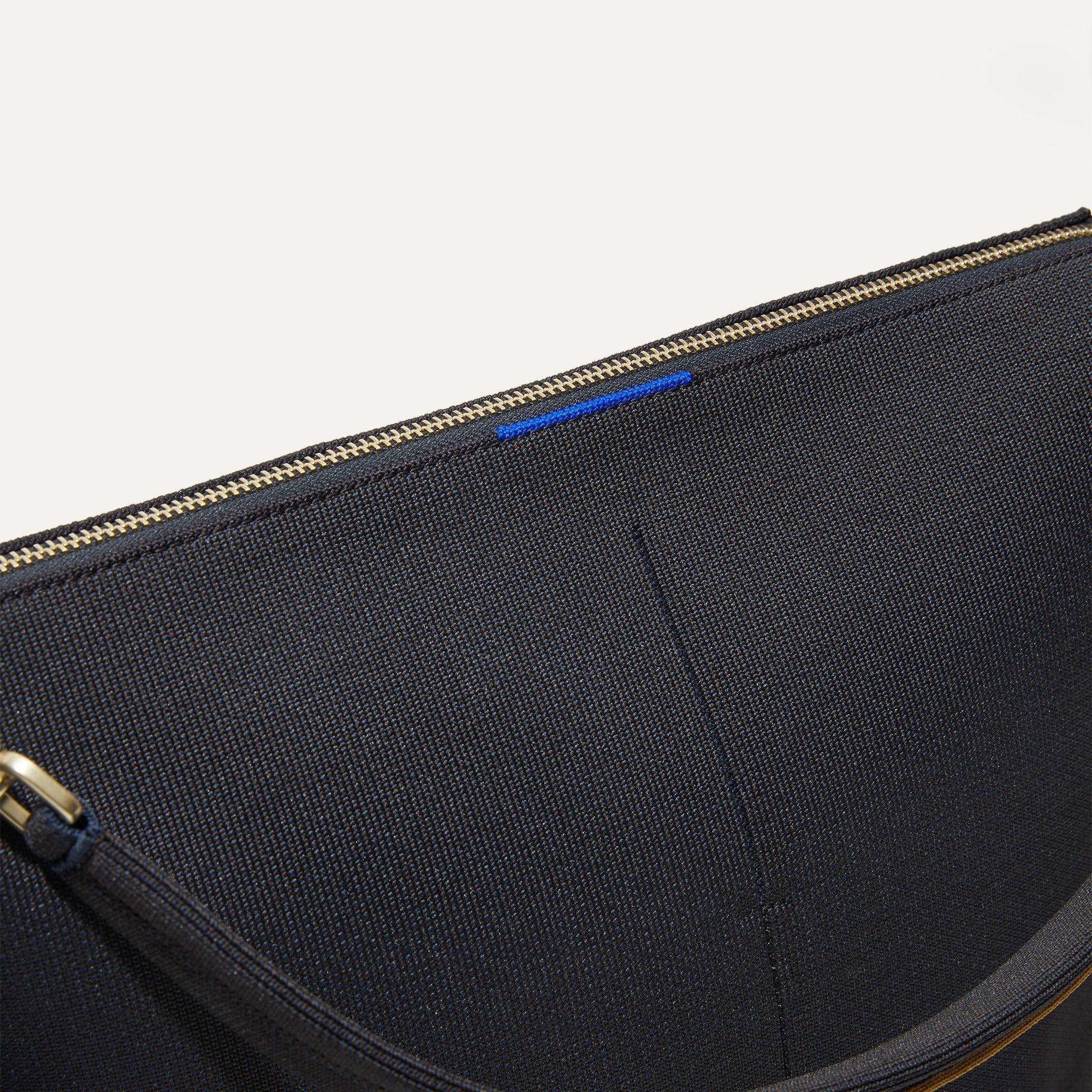 A closeup of The Mini Zip Bucket in Ink and Ivory, showing the smooth zipper closure and soft, flexible handle.