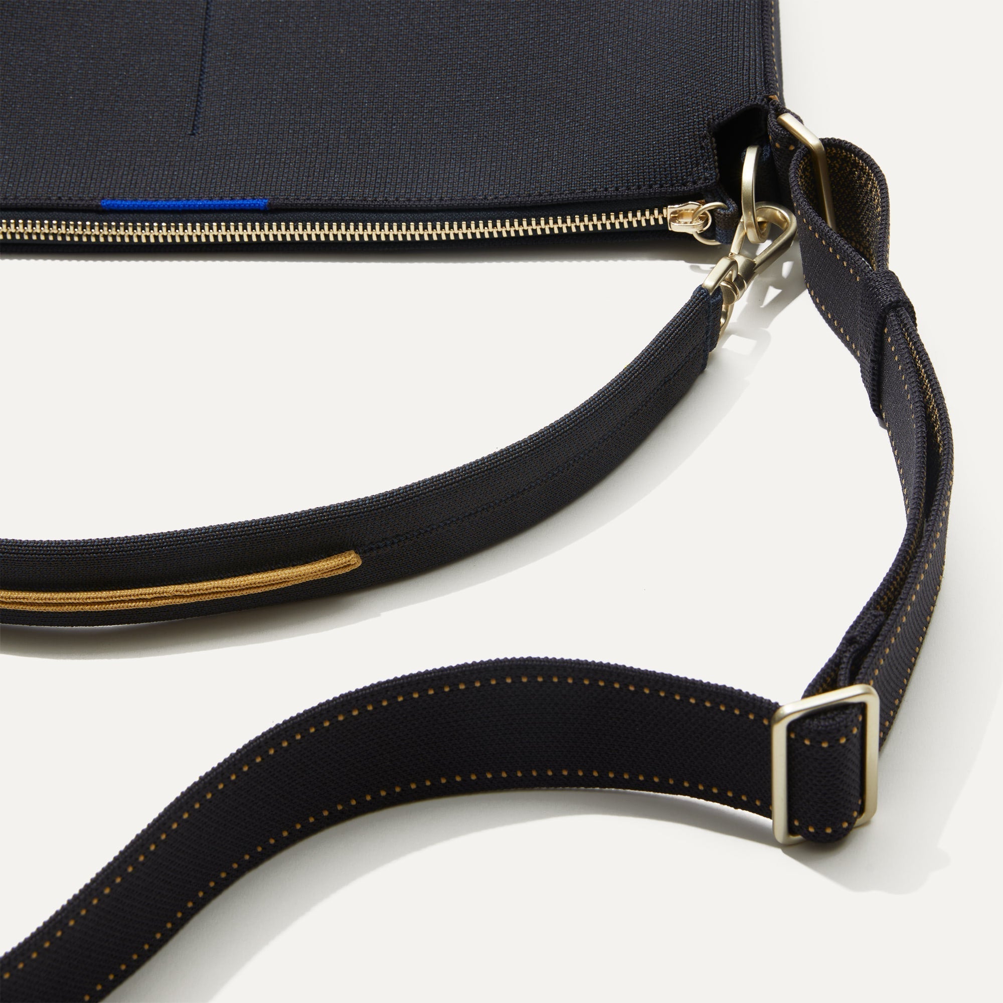 A closeup of The Mini Zip Bucket in Ink and Ivory lying flat, showing the detachable top handle and adjustable crossbody strap.