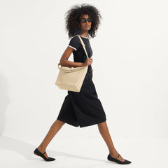 The Mini Zip Bucket in Knot Brown worn as a crossbody by a female model, shown in motion from the right.