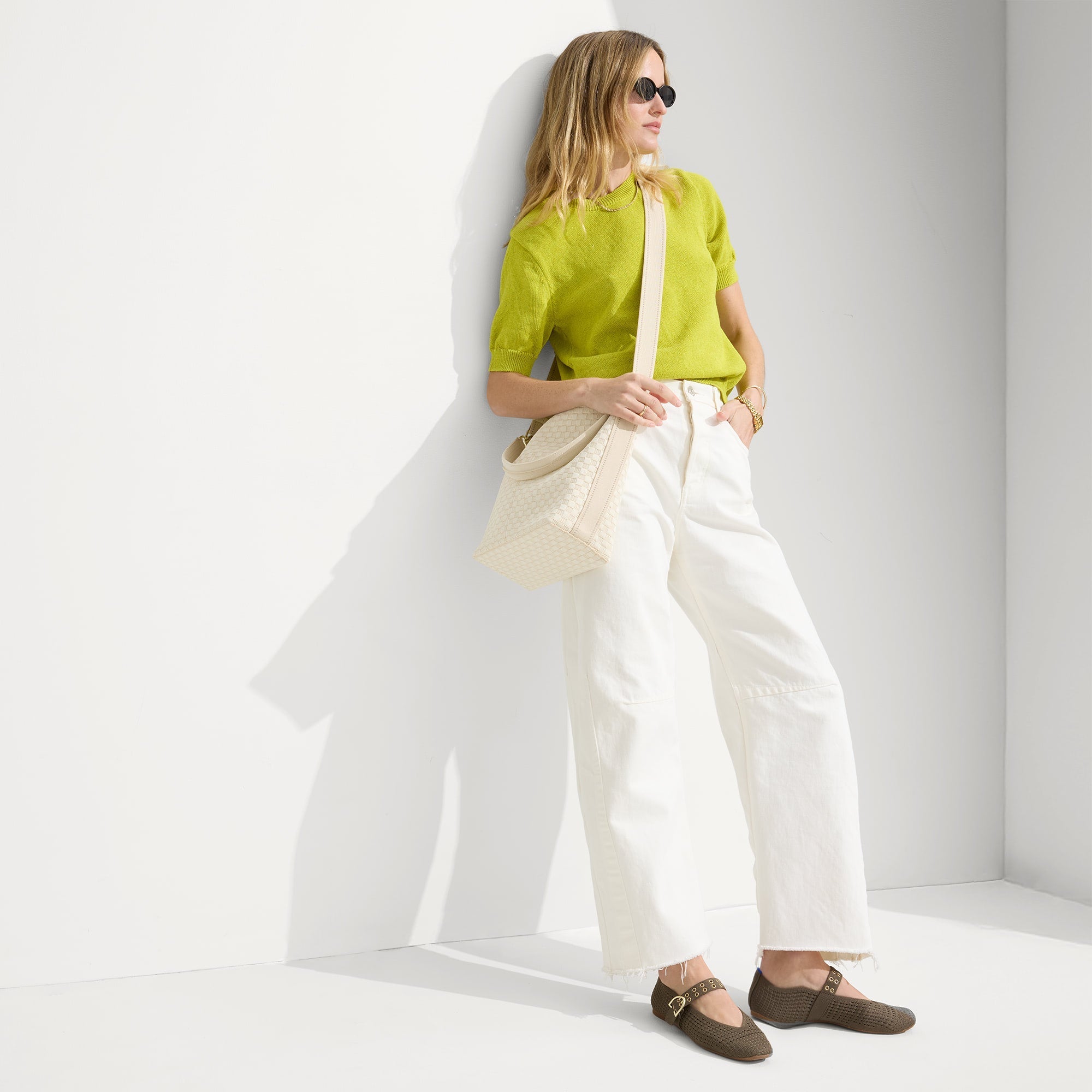 hover | The Mini Zip Bucket in White Sand, carried over the shoulder of a female model, shown from the front.