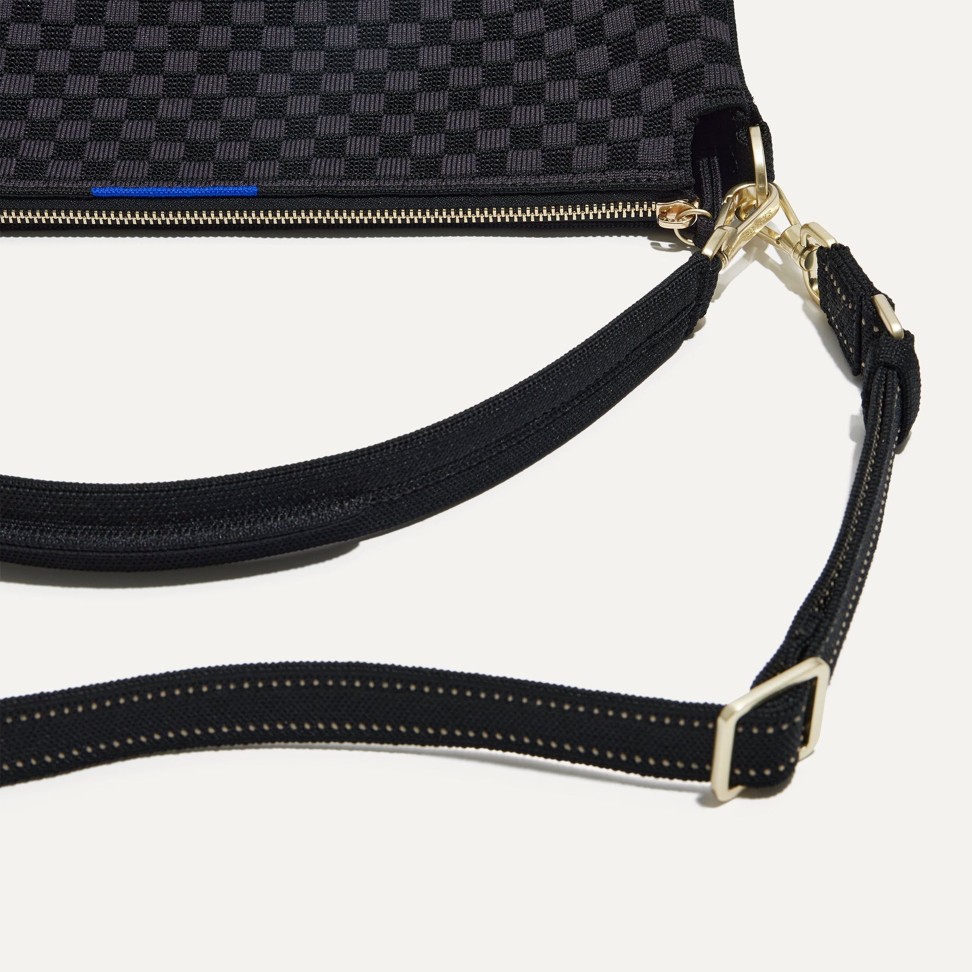 A closeup of The Daily Crossbody Bag in Black Sand, showing the smooth zipper closure and soft, flexible handle.