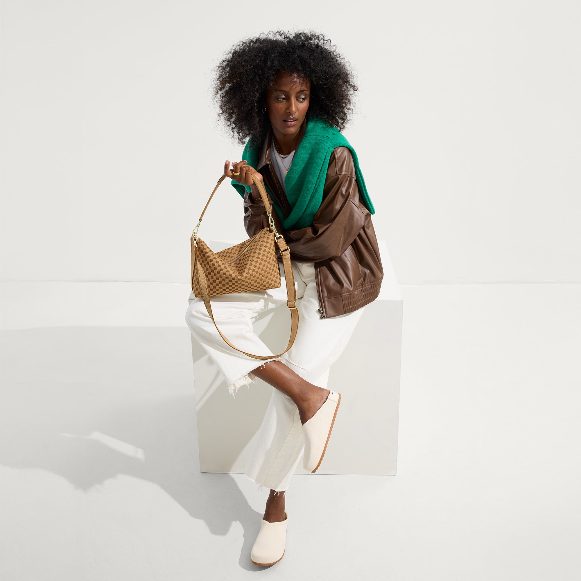 The Daily Crossbody in Hazelnut, carried by its top handle by a female model, shown from the front.