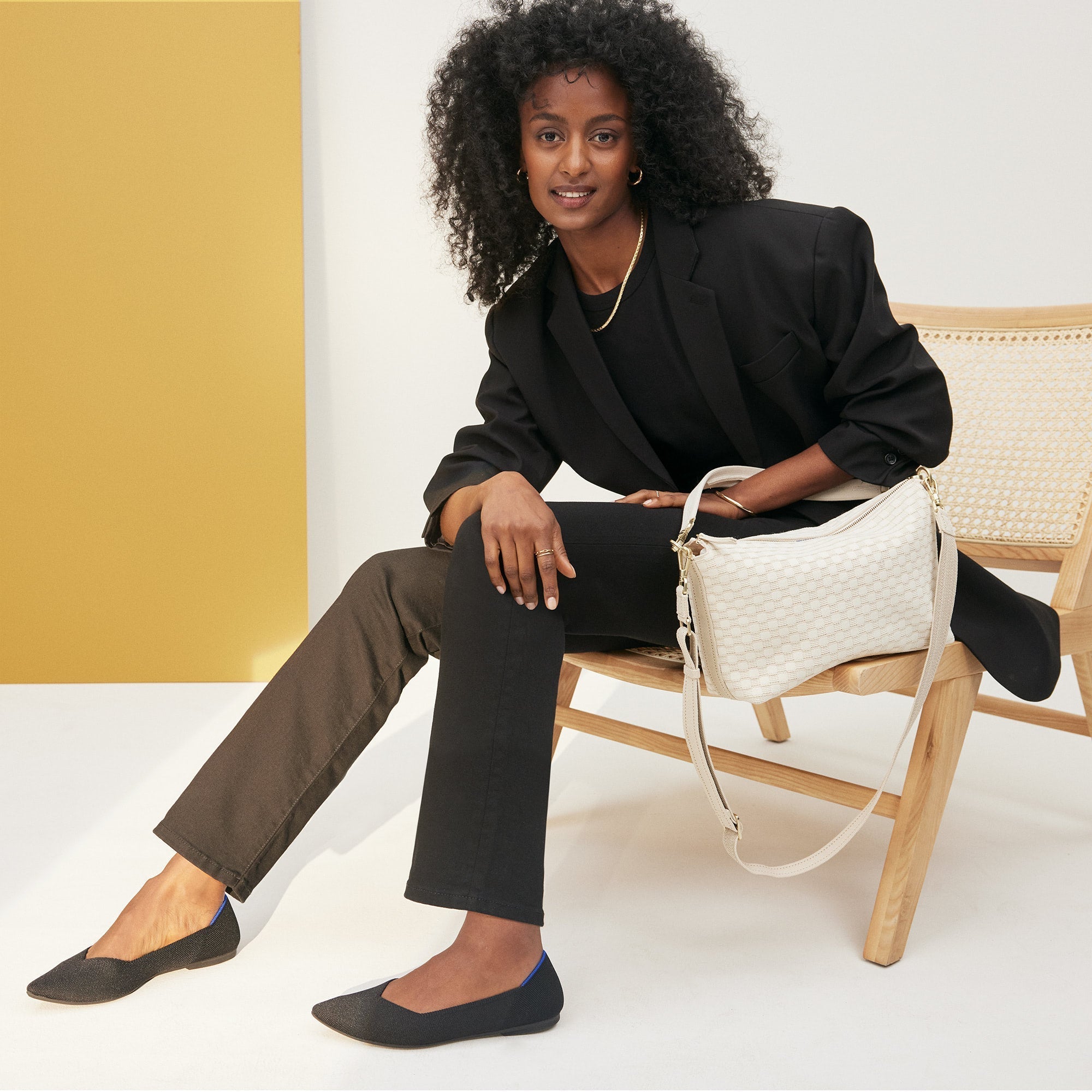 hover | The Daily Crossbody in White Sand, carried by its top handle by a model.