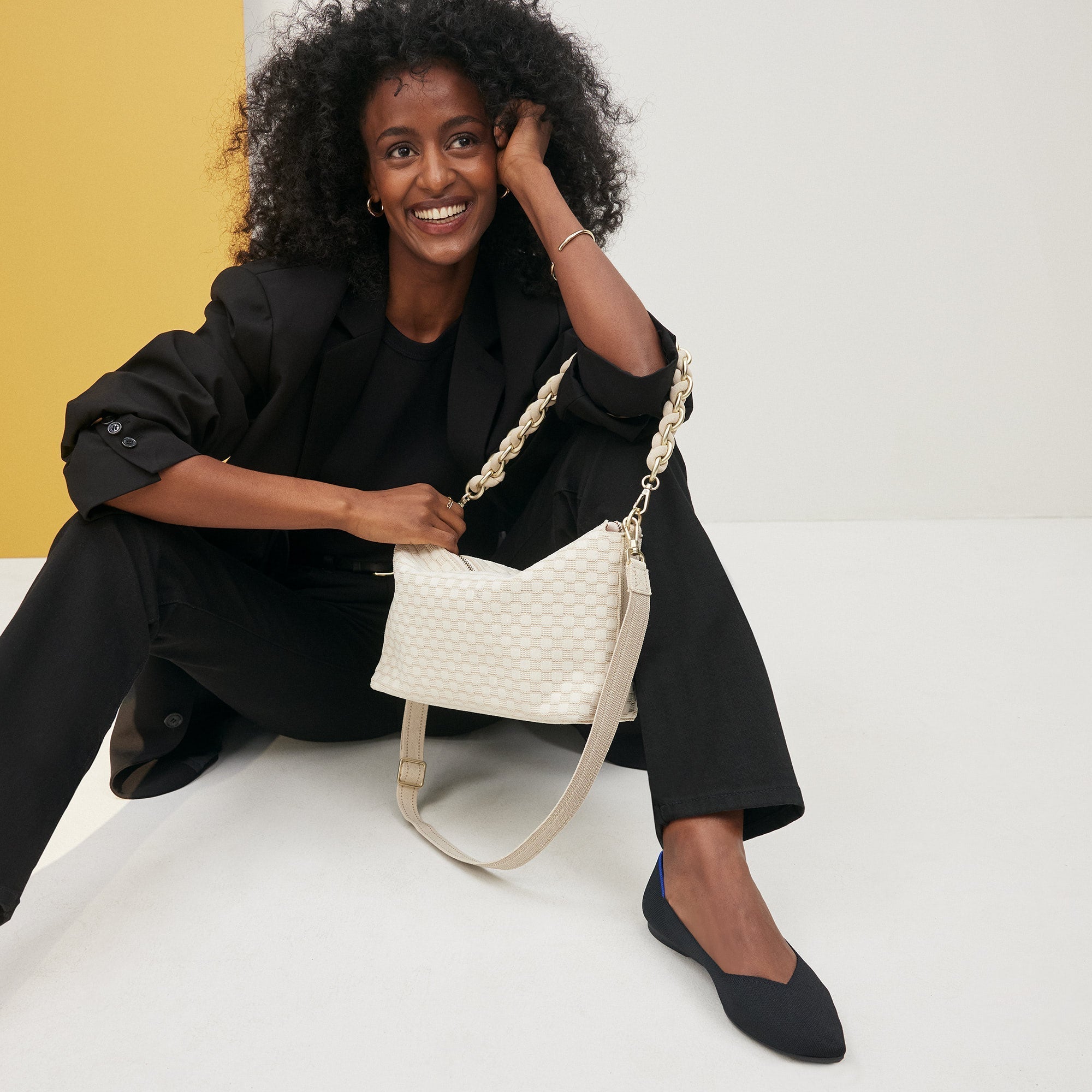 An alternate image of The Shoulder Strap in White, shown paired with The Daily Crossbody and held by a model.