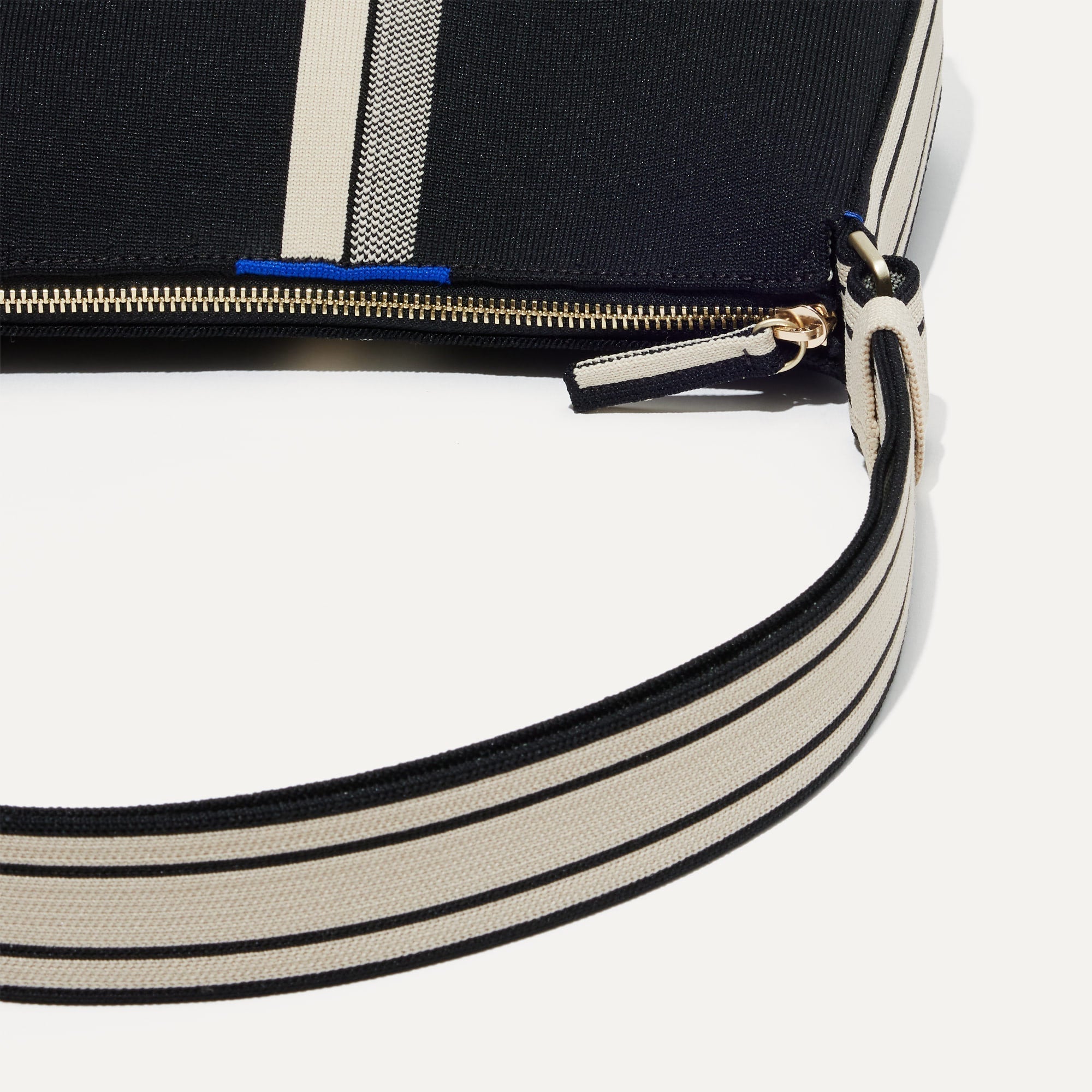 A closeup of The Casual Crossbody in Black & Ivory Stripe, focusing on the crossbody strap. 