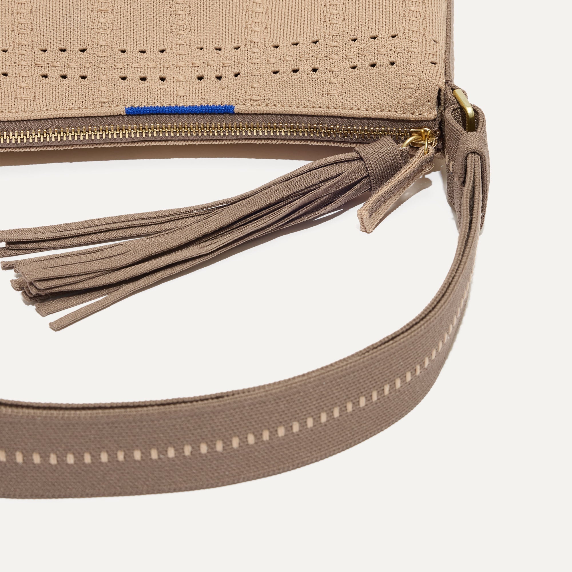 A closeup of The Casual Crossbody in Brown Perf, focusing on the crossbody strap. 