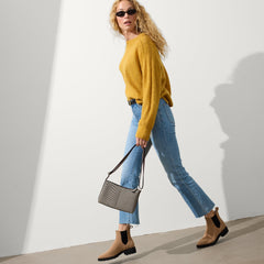 The Casual Crossbody in Dark Mist, carried by its crossbody strap by a model, shown in motion.