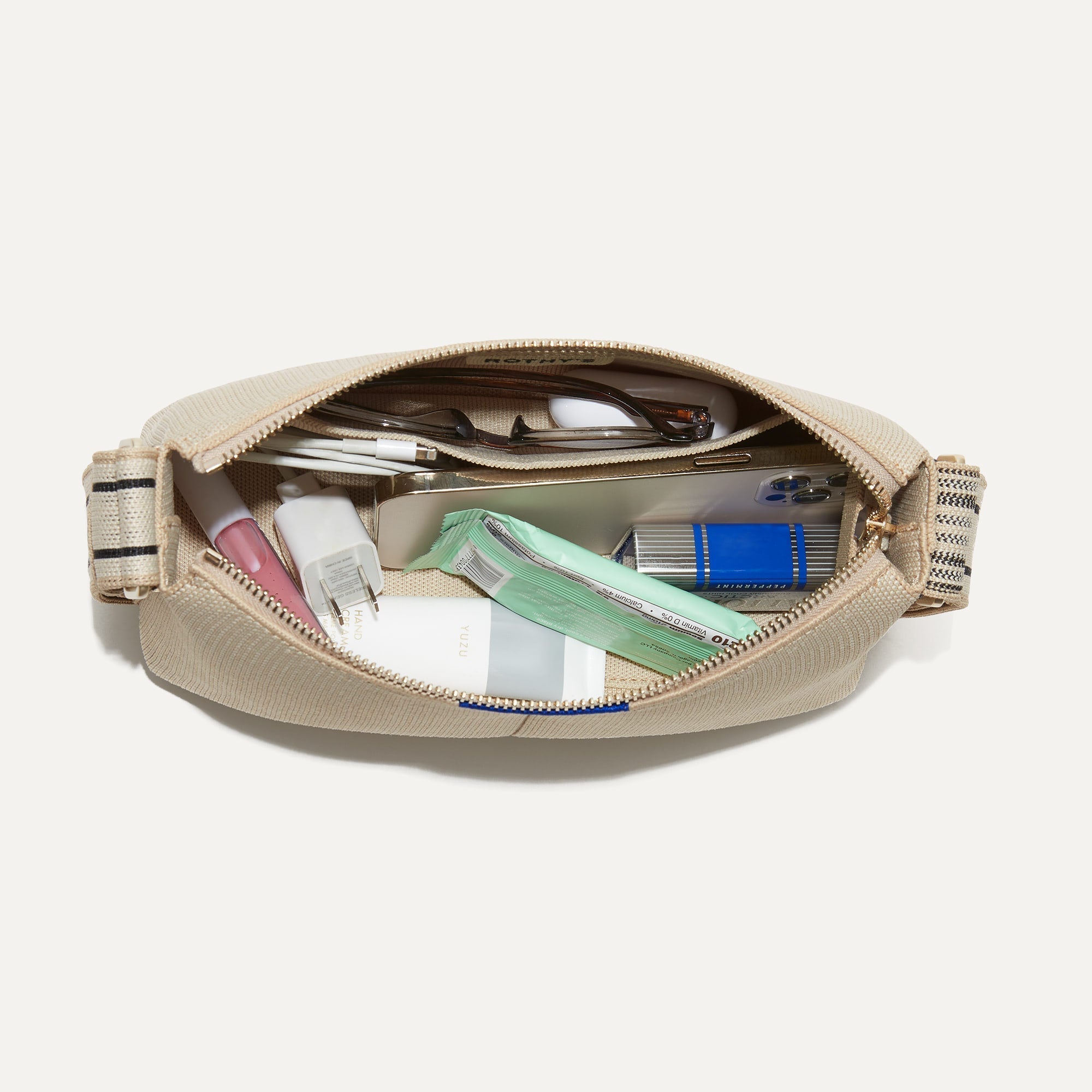 The Casual Crossbody in Parchment, shown from above, with the interior exposed and packed with items.