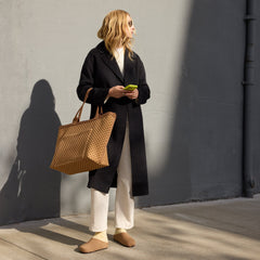 An alternate view of a model holding The Zip Travel Tote in Hazelnut.