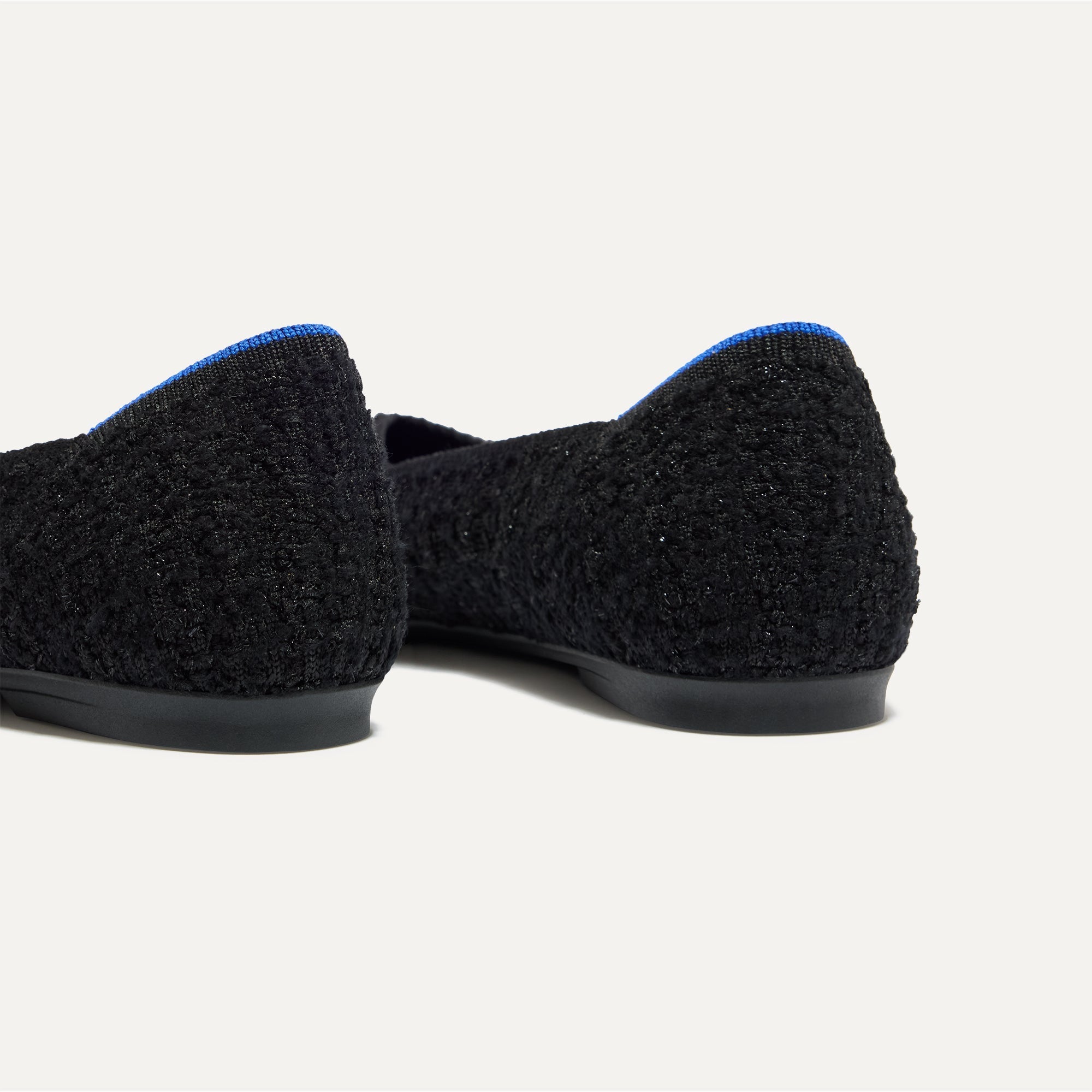 Close up of the heel of The Point II in Black Bouclé, with Rothy's signature blue halo. 