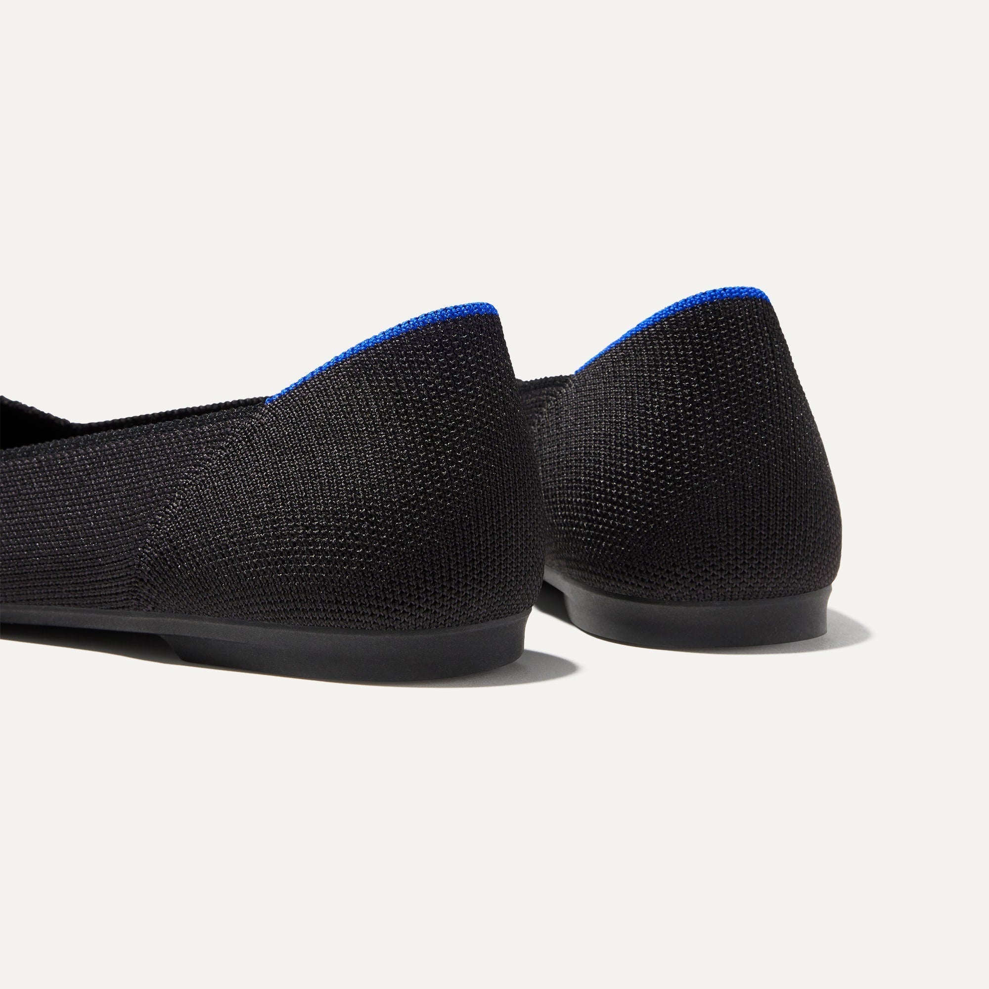 Close up of the heel of The Point II in Black, with Rothy's signature blue halo. 