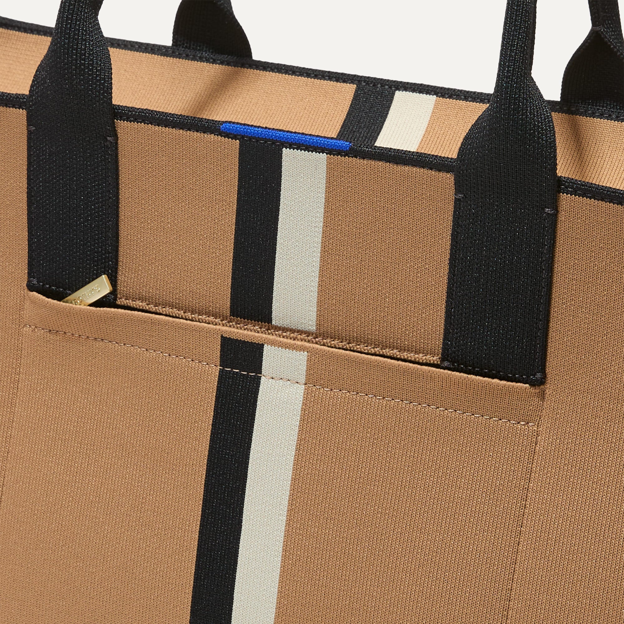 A closeup of The Classic Tote in Grand Piano, focusing on the exterior zip pocket. 