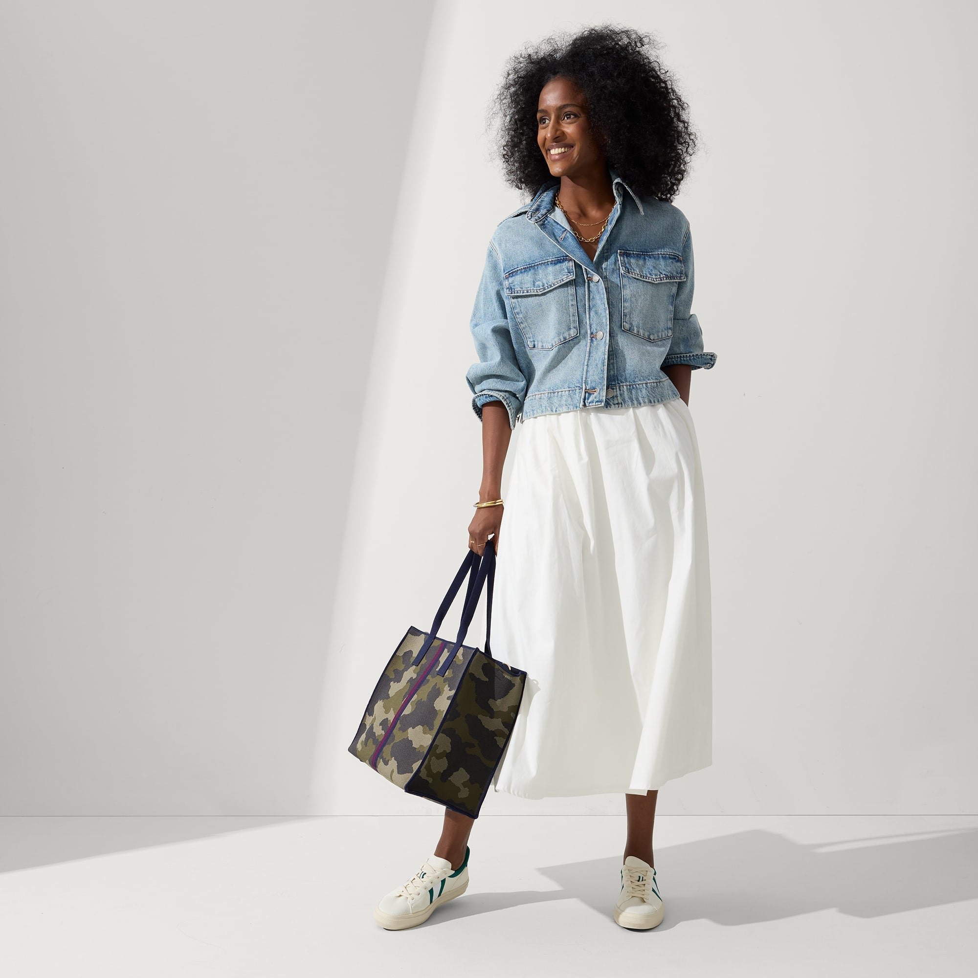 The Classic Tote in Spruce Camo, carried by its top handles by a model, shown from side.