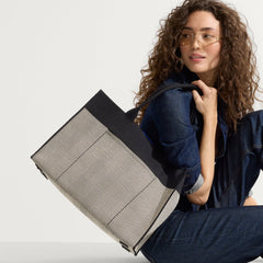 hover | The Classic Tote in BlackHerringbone, carried by its top handles by a model, shown from side.