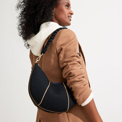 An alternate image of The Braided Shoulder Strap in Black, shown paired with The Crescent Bag and held by a model. 