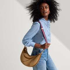 The Crossbody Strap in Confetti Stripe, shown paired with The Crescent Bag, worn by a model, shown from the side