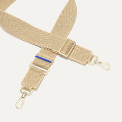 A close-up of The Crossbody Strap in Gold Dust, focusing on the end snap hooks and sliding buckle.