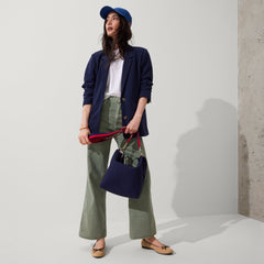 The Crossbody Strap in Navy & Red, shown paired with The Mini Zip Bucket, worn by a model, shown from the side.