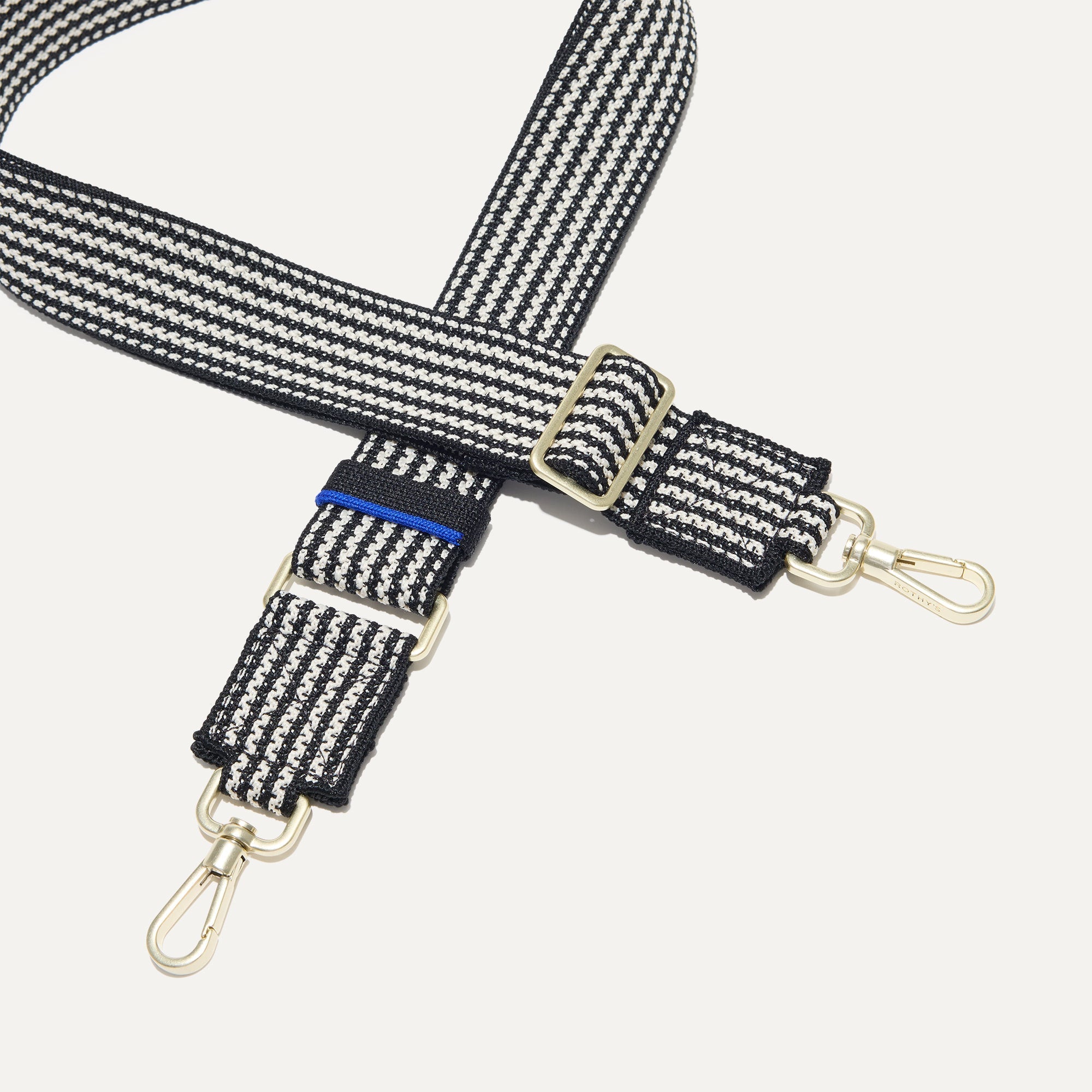 A close-up of The Crossbody Strap in Salt and Pepper, focusing on the end snap hooks and sliding buckle.