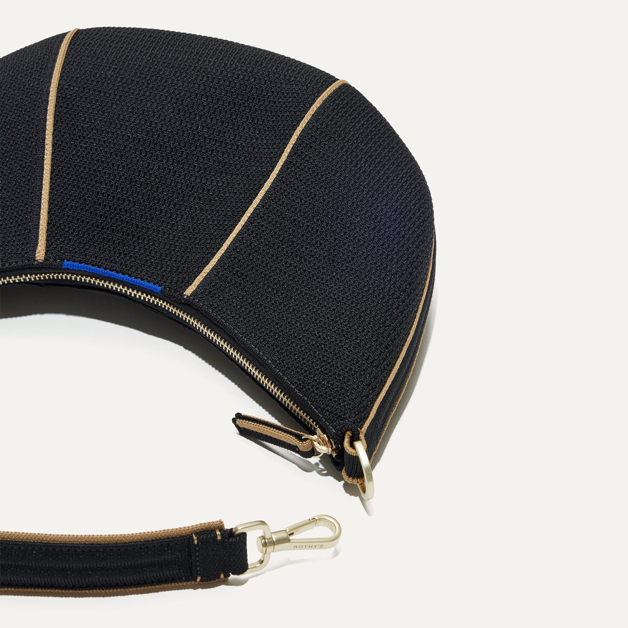 A close up of The Crescent Bag in Black, with the shoulder strap detached. 