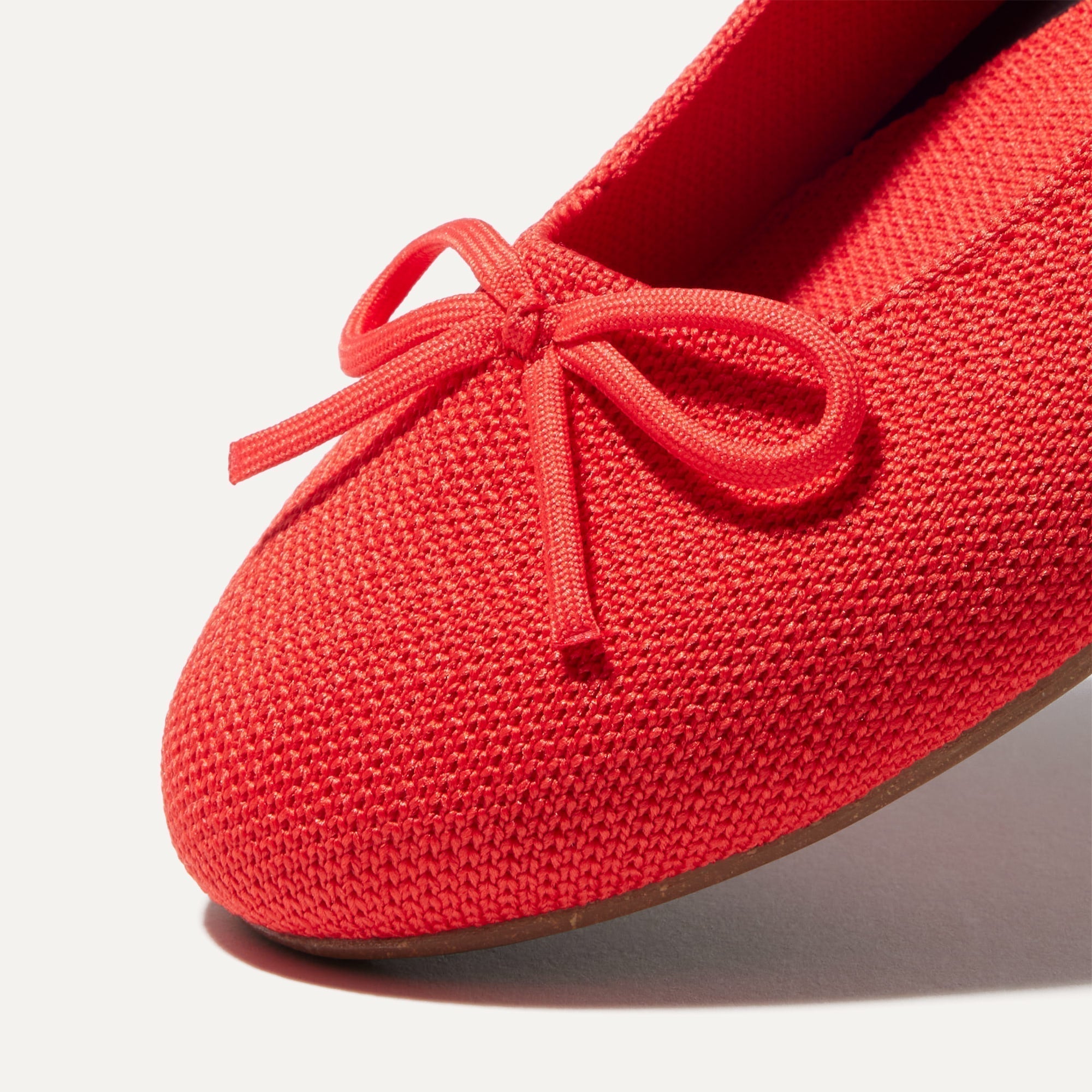 Close up of the rounded toe and bow detail of The Ballet Flat in Glamour Red.