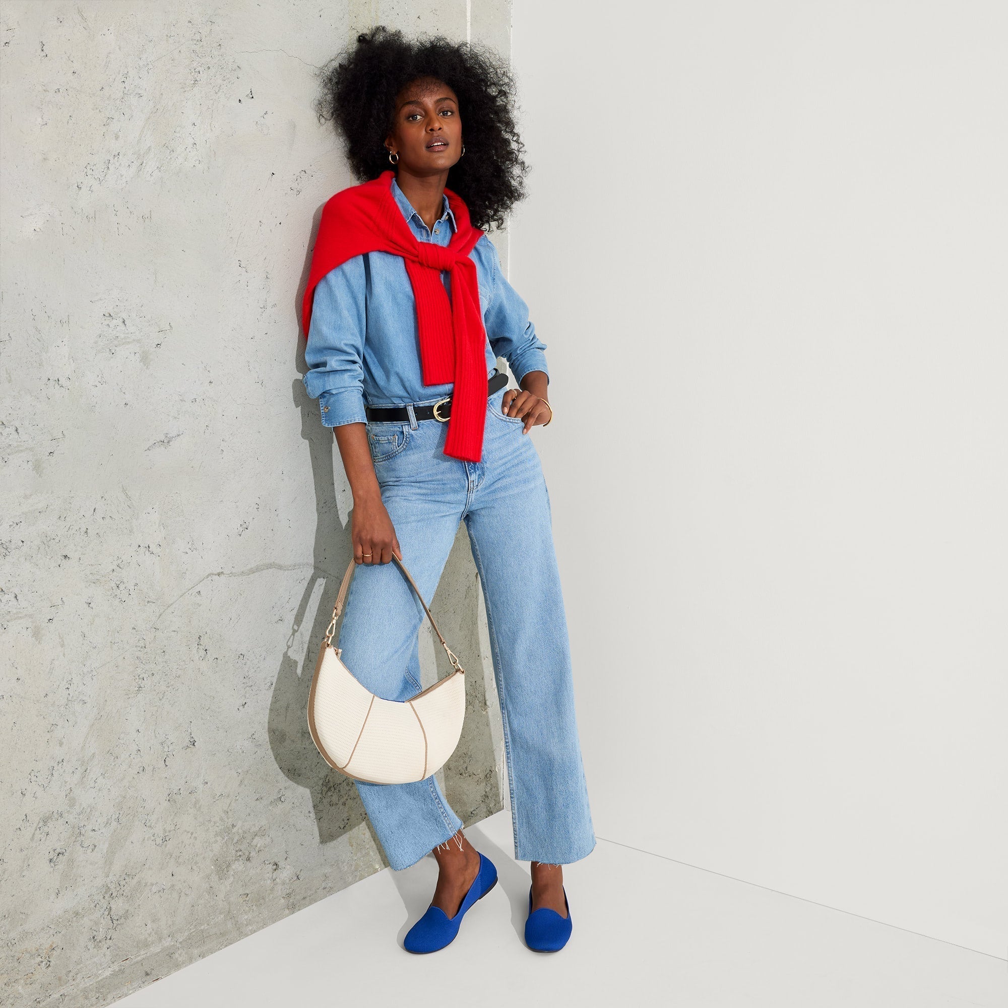 Another view of model holding The Crescent Bag in Celestine by the shoulder strap, shown in motion. 