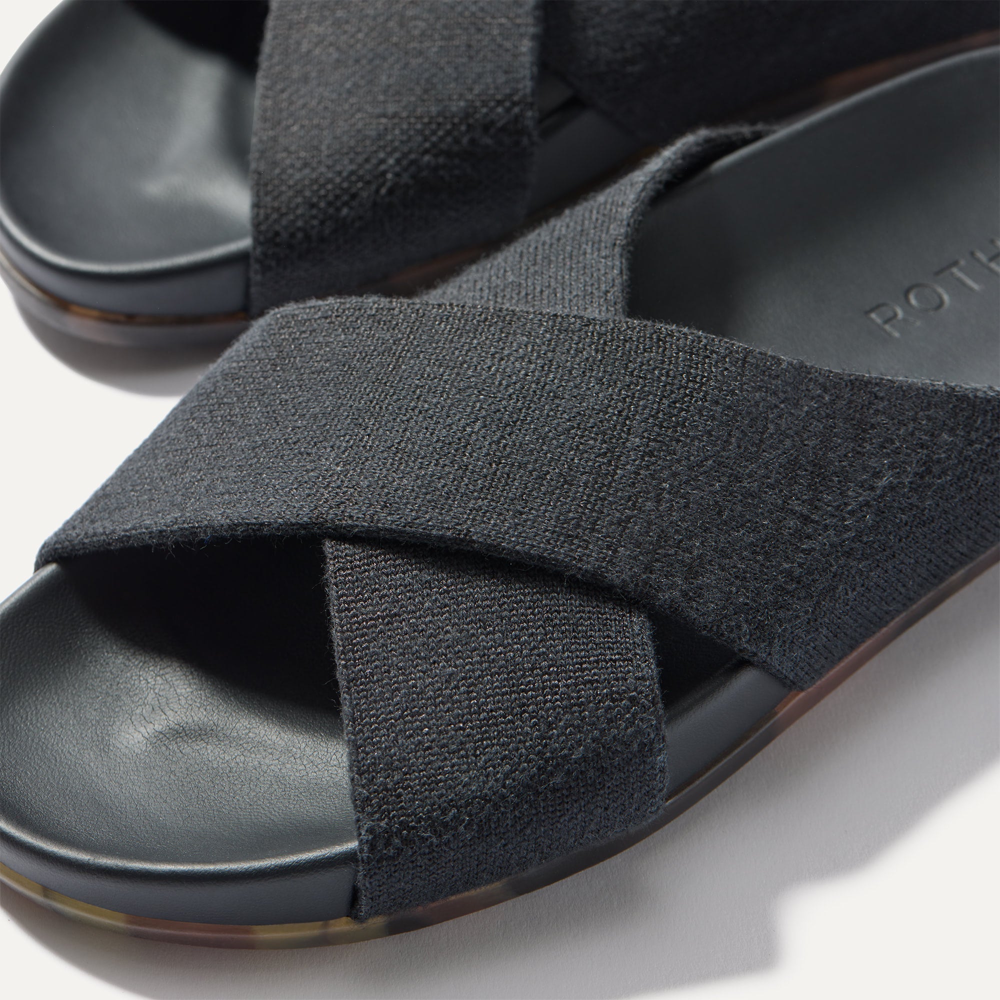 Close up of the crossing knit straps and toe of The Weekend Slide in Black, shown in diagonal view. 